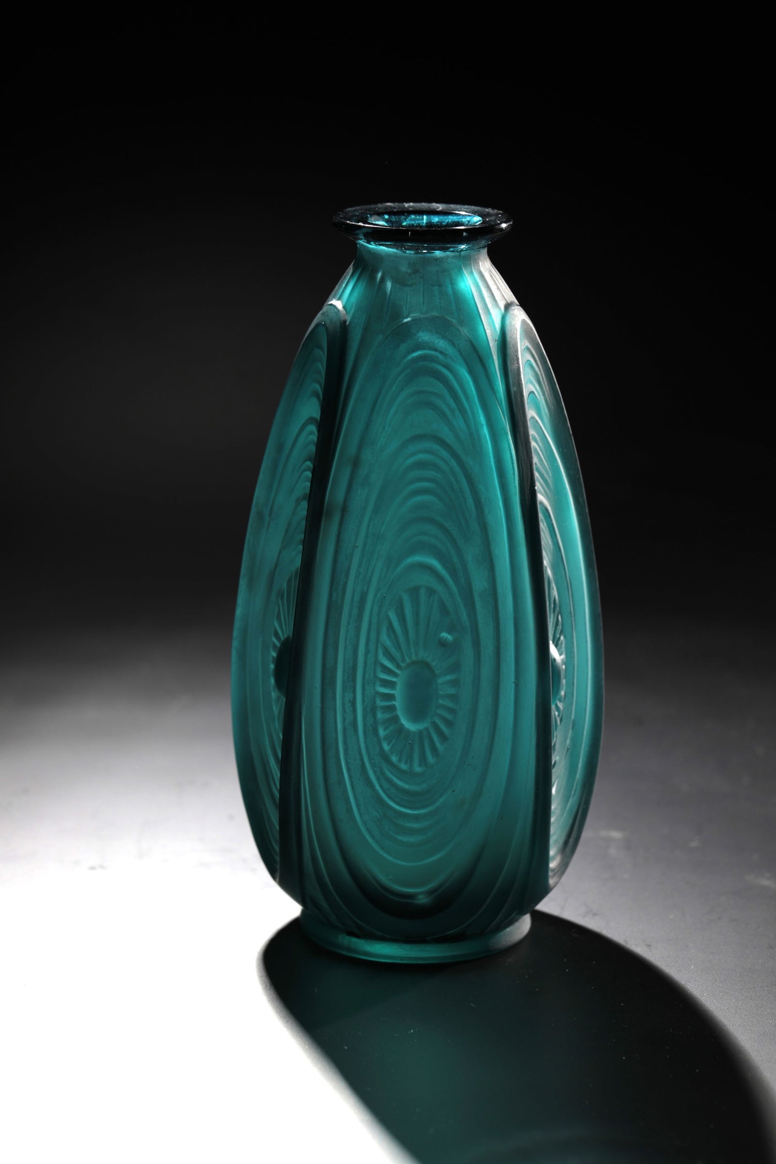 Vase ''Les alvéoles'': Vase ''Les alvéoles'' Marius Sabino, 1928 Petrol blue glass, compression moulded. Repeating relief decoration all around. Underside labeled: Sabino France (in diamond crack). H. 17 cm Lit.: G. Cappa,