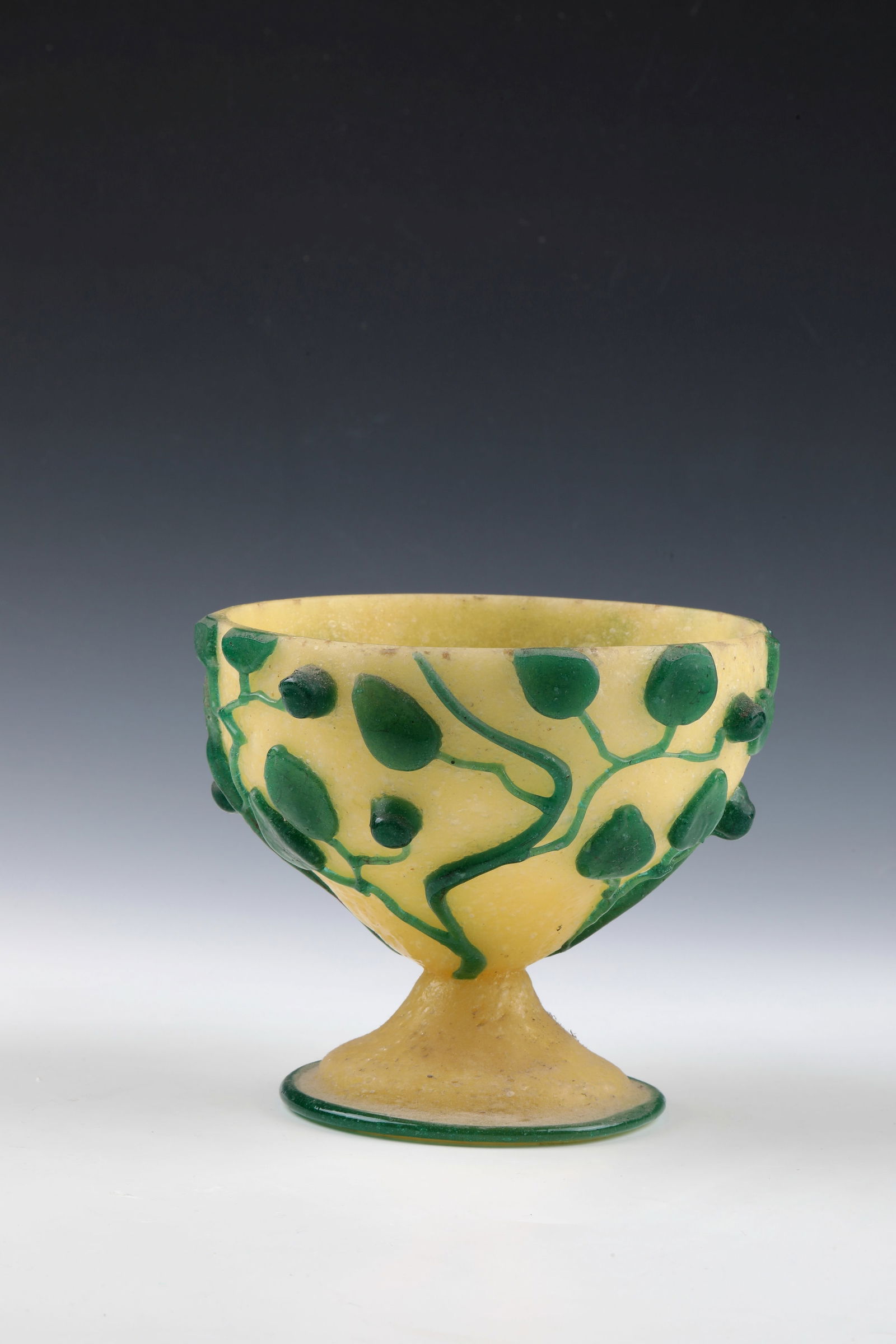 Foot shell: Foot bowl Jean Sala, c. 1925 Light yellow foam glass with sculpturally applied leaf branches and berries in green. Foot edge with green thread. On one of the sheets inscribed: Jean Sala (diamond-scrat