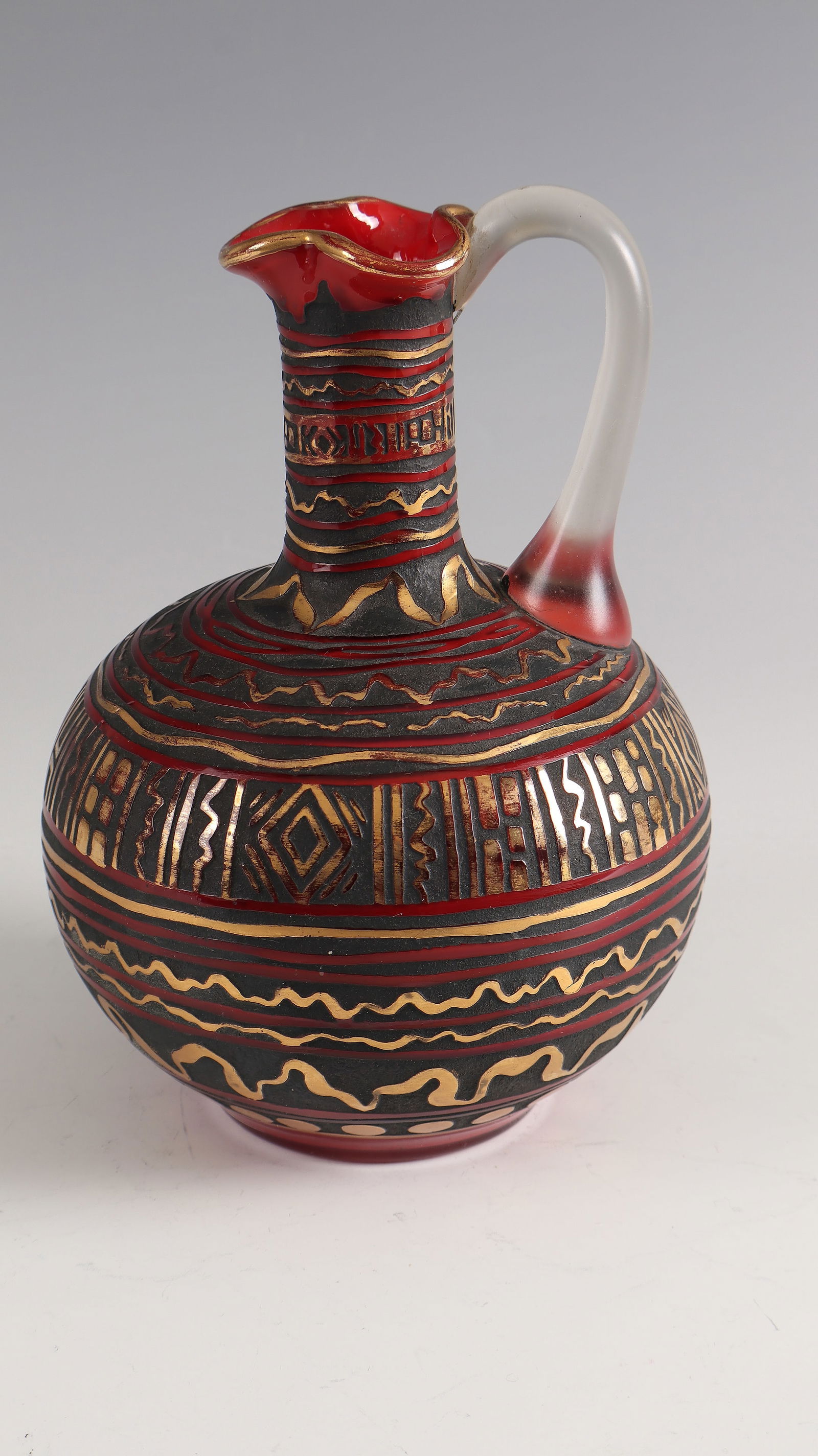Ball belly jug: Kugelbauchkrug Loetz Wwe., Klostermühle, 1928 Colourless, opaque red underlaid glass. Etched decoration, partially dark green patinated or rubbed with gold. Attached handle in colorless. H. 20 cm
