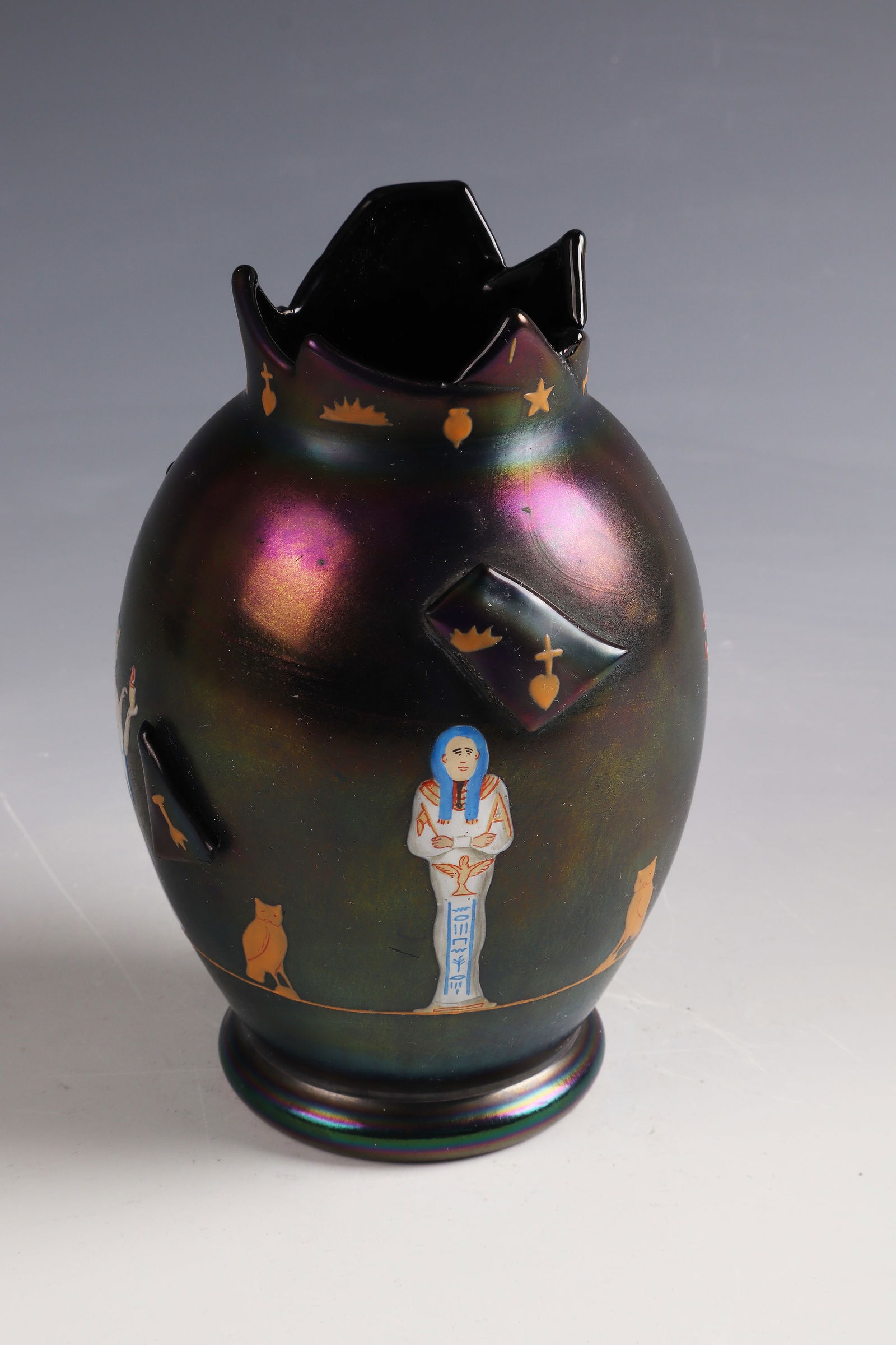 Vase with Egyptianizing figure frieze: Vase with Egyptian-style figure frieze L. Moser & Söhne, Karlsbad, c. 1900 Dark violet glass with gold and multicolored opaque enamel decoration. With applied glass plates in dark purple. Vigorously