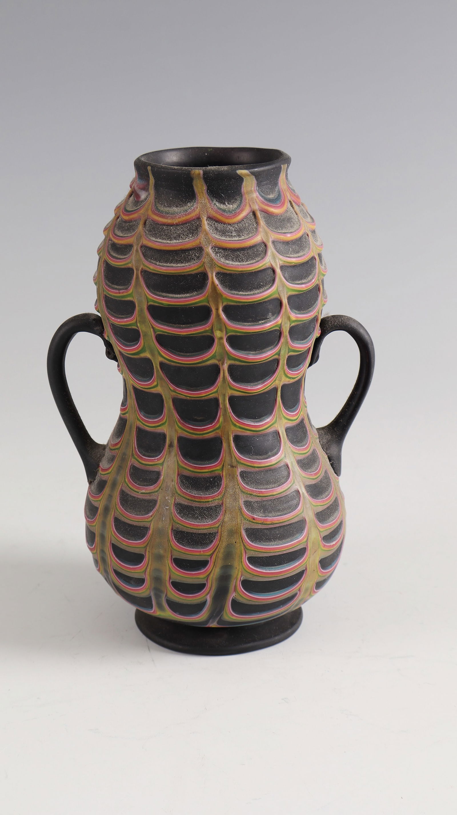 Handle vase ''Fenicio'': Handle vase ''Fenicio'' Fratelli Toso, Murano, c. 1900 Opaque black glass with fused, wavy combed multi-coloured glass threads. H. 16.5 cm Lit.: Exhib. cat.: Murrine e Millefiori nel Vetro di Murano