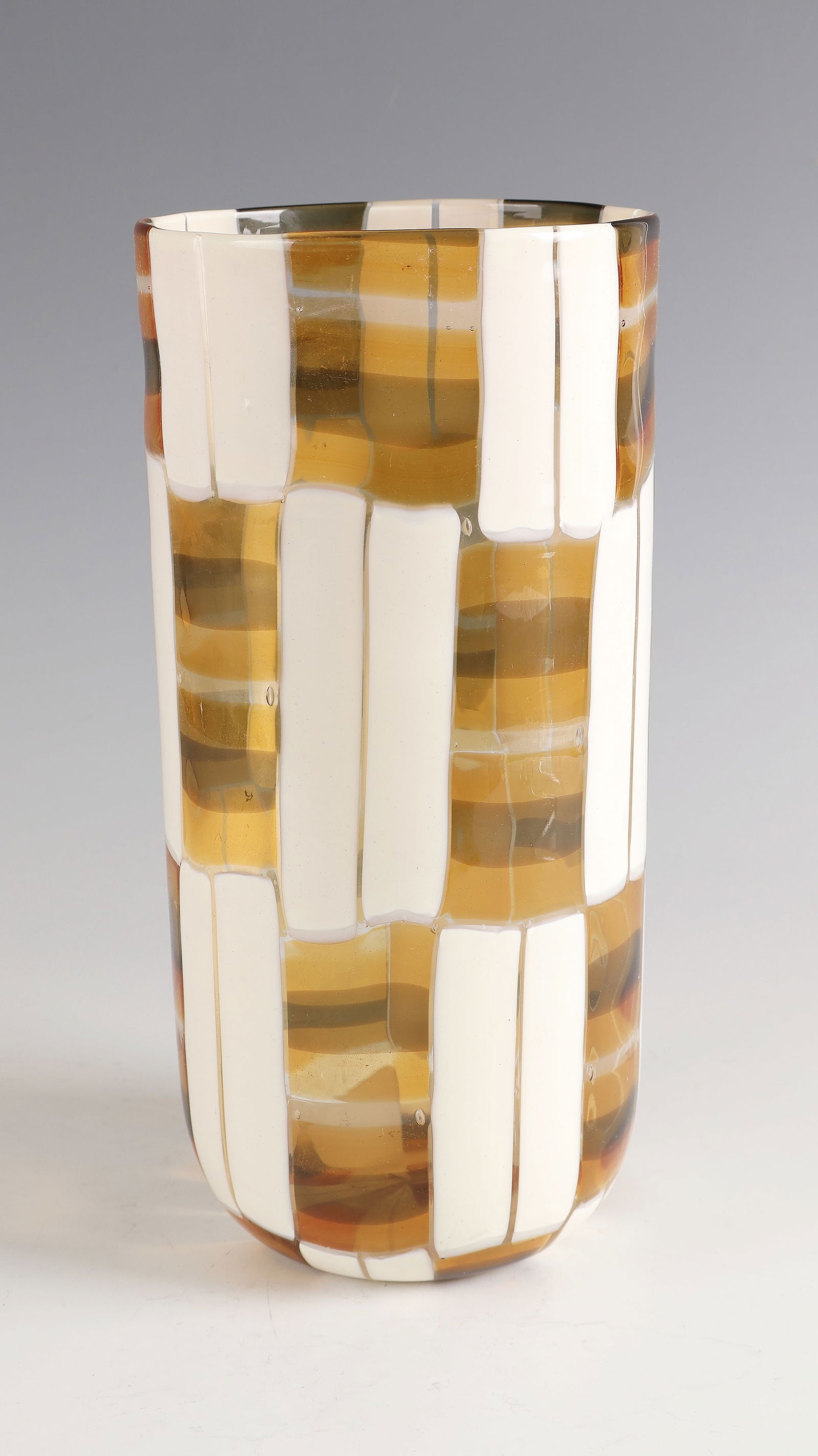 Cylinder vase ''Pezzato'': Cylinder vase ''Pezzato'' Murano, 70s Colourless glass with horizontally and vertically melted plates ('tessere') in white ('lattimo'), honey yellow and grey. H. 28 cm Lit.: G. Cappa, Le Genié Verrie