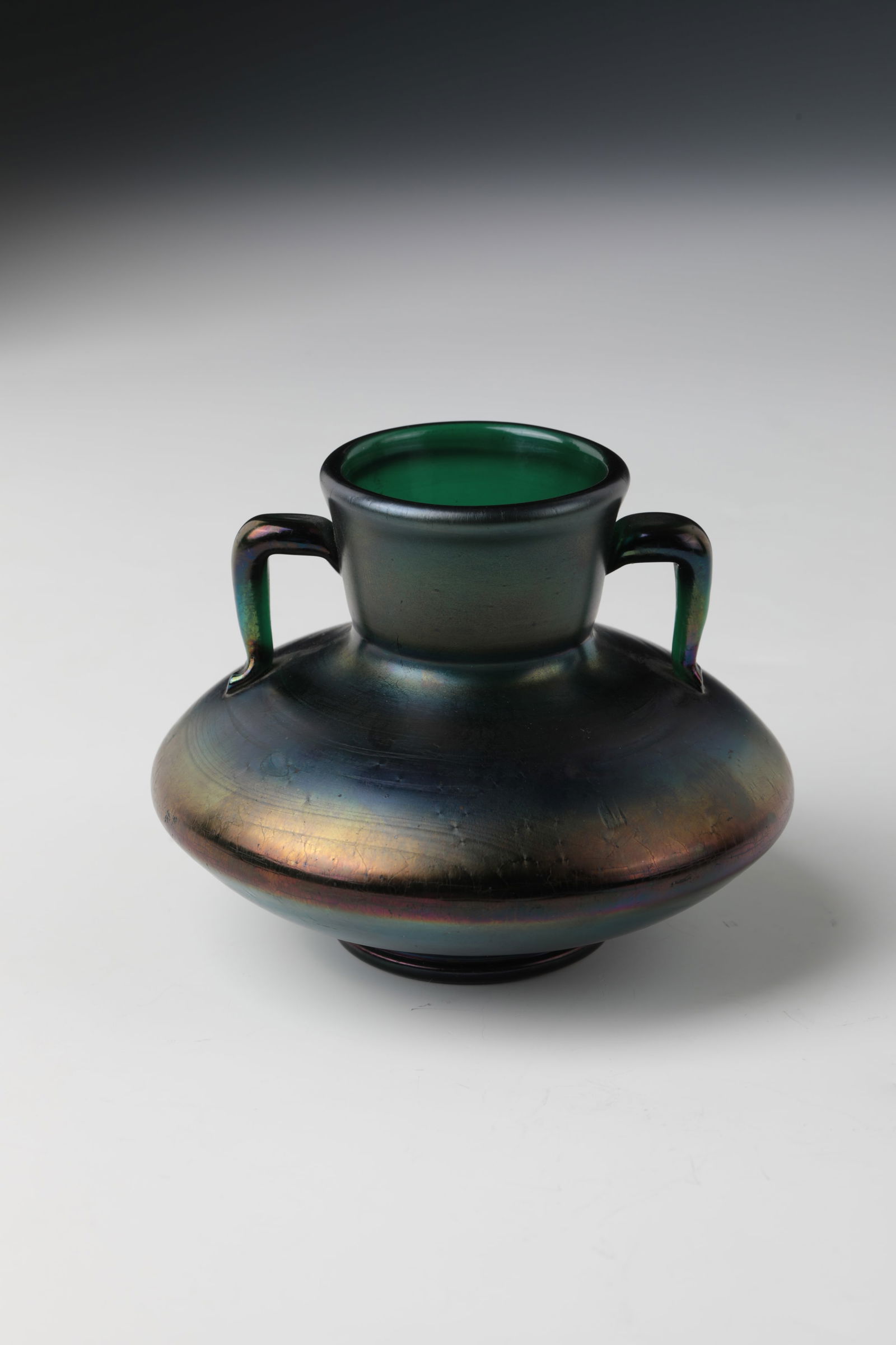 Small Handle Vase: Small Handled Vase Bavarian Forest or Bohemia, around 1900 Dark green, iridescent glass with ground tear-off. Pressed wall, slightly widened neck with appliquéd handles. H. 8 cm