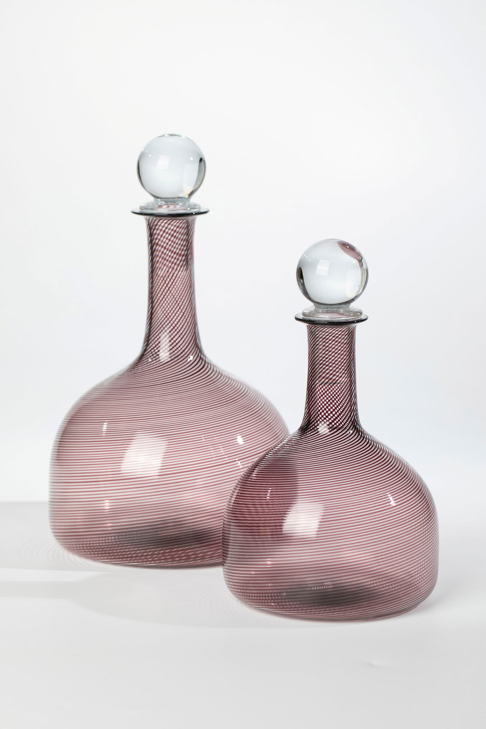 Pair of bottles with stopper ''Mezza filigrana'': Pair of bottles with stoppers ''Mezza filigrana'' Wohl Venini for Compagnia di Venezia e Murano - Pauly & C., c. 1935 Colourless glass, with black-violet threads melted diagonally. H. 18.5 - 22.5 cm.