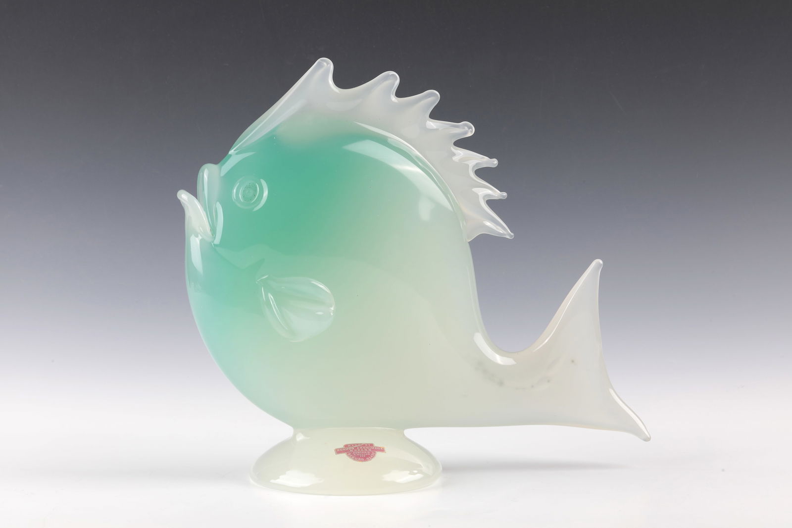 ''Pesce'': ''Pesce'' Archimede Seguso, Murano, c. 1950 Colourless glass, underlaid with white and green opal. Freely formed and pinched with pliers. On the round stand original foil label. H. 27 cm; L. 32 cm.