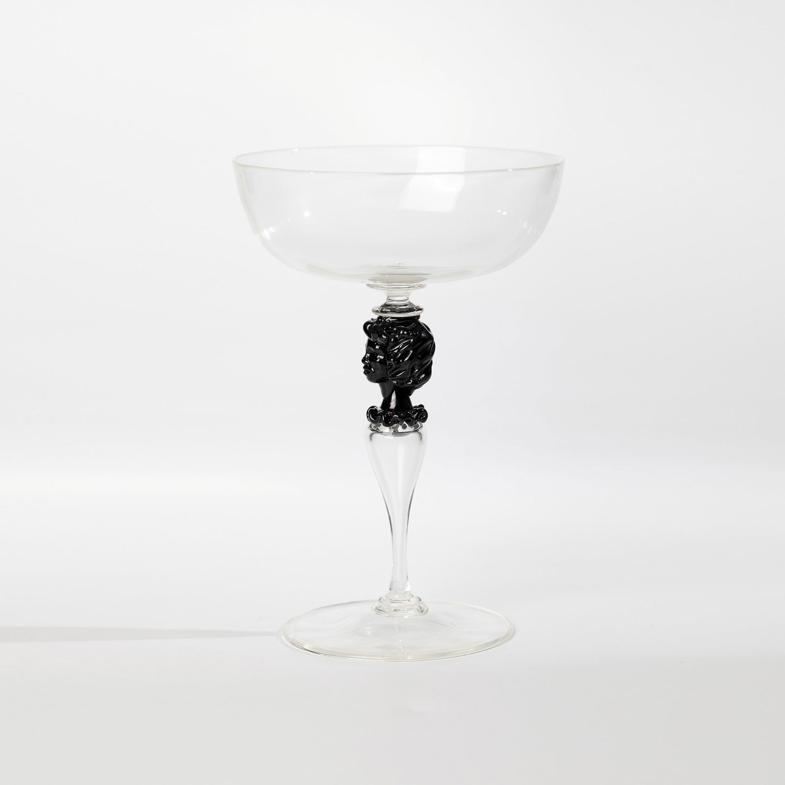 Champagne bowl: Murano Champagne Bowl, circa 1910 Thin-walled, colourless and black-violet glass. Hollow baluster shaft between disc nodi. Bowl-shaped cuppa. Nodus in the form of a bust. The round disc base with the