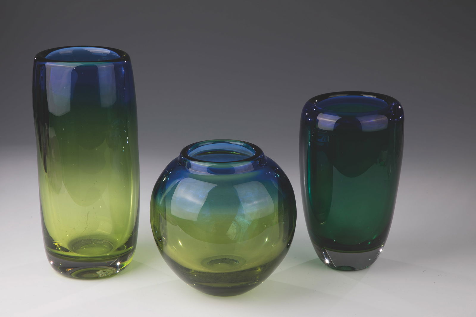 Three Vases: Three vases Hartmut Bechmann Colourless, thick-walled glass with running underlays in blue and yellow or green. Underside with incised monogram ''Be''. H. 17.5 to 27 cm.