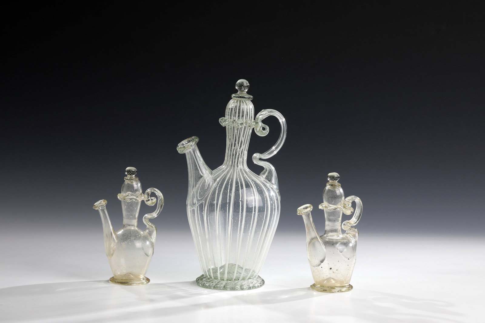 Three pharmacy pots: Three pharmacy pots Italy, altars or Tuscany, 17th century Colourless, slightly greenish glass, one with melted frosted glass threads. Raised floor with demolition. Pinched stand ring. Extended spout 