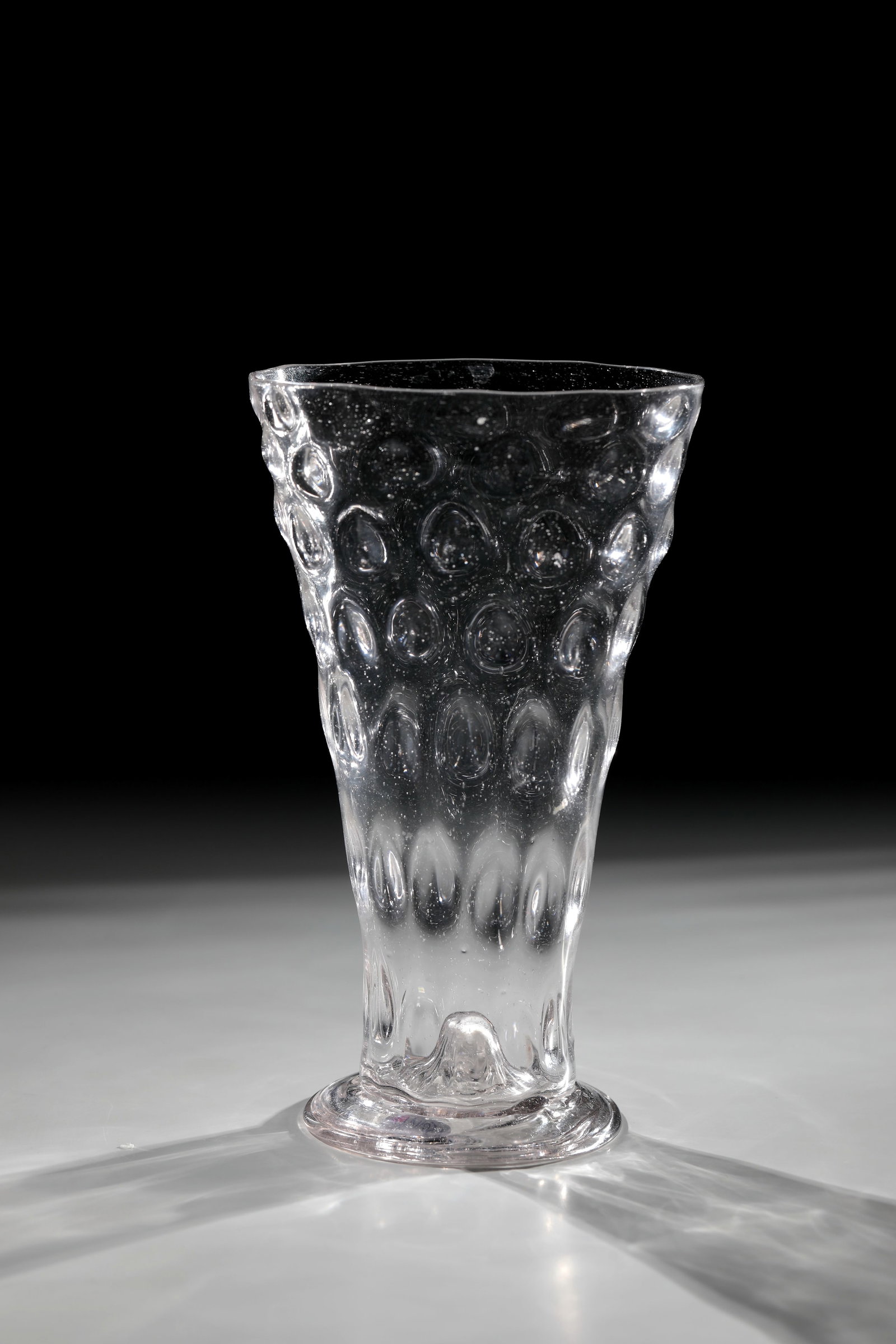 Wart cup: Wart cup Germany, 17th century Colourless, slightly manganese-tinged glass with tear. Spun, fused foot with raised bottom and bottom rosette. Conically widened wall with optical wart decoration. H.