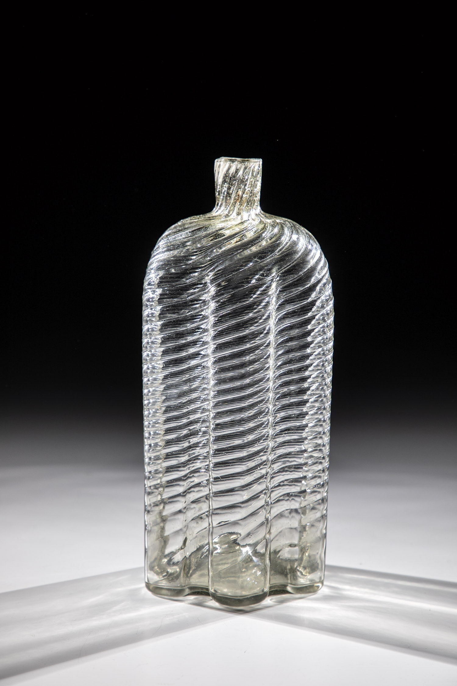 Rare six-pass ribbed bottle: Rare six-pass ribbed bottle Venice, 17th century Greyish, very light glass. Slightly raised floor with tear-off. The cross-section of the wall is hexagonal, with oblique optical decoration. Short tube