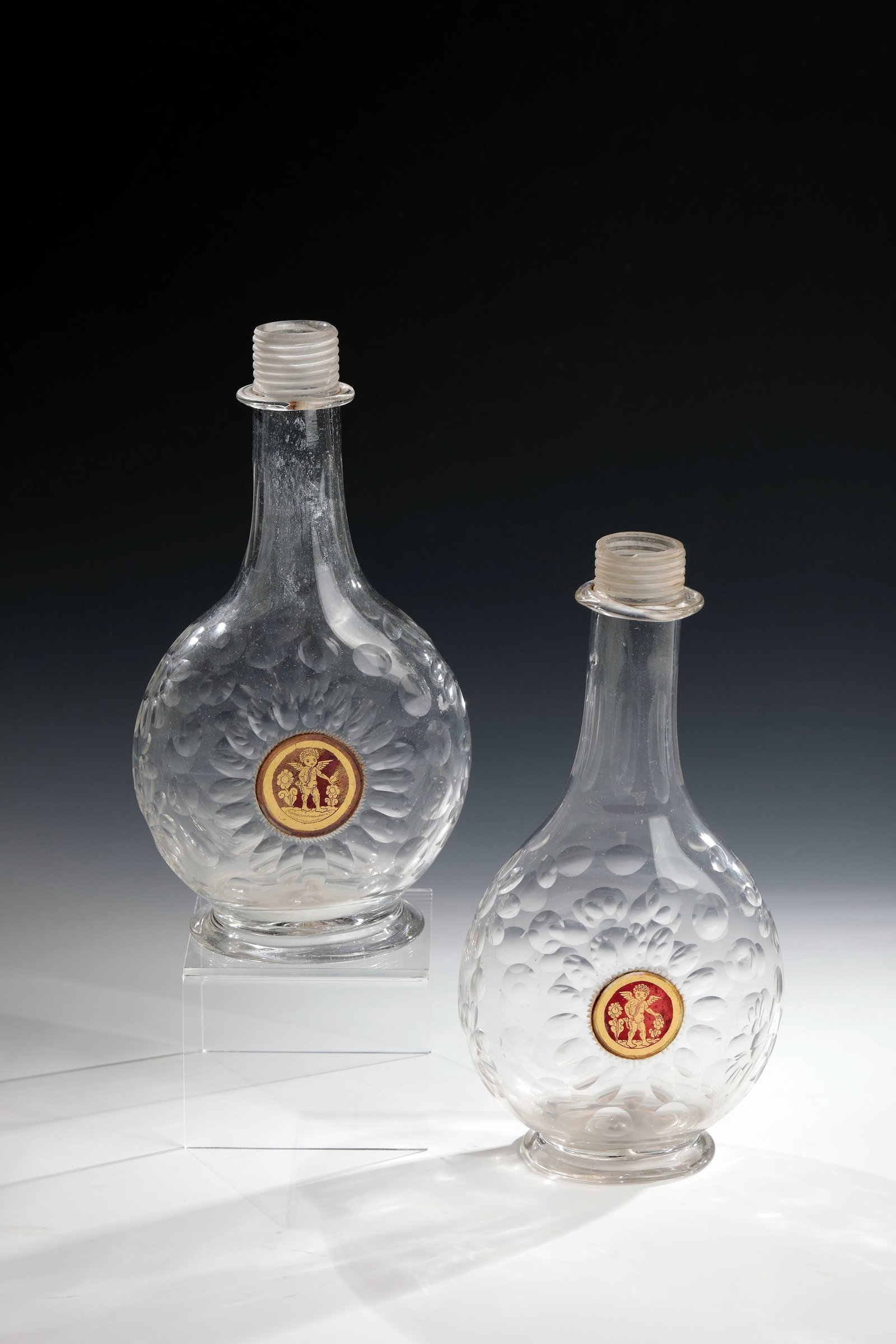 Pair of bottles with intermediate gold medallion: Pair of bottles with intermediate gold medallion Giant Mountains, 1H. 18th century Colourless, slightly greyish tinted glass with tear-off. Bulbous, flattened body on both sides with rich olive and sp