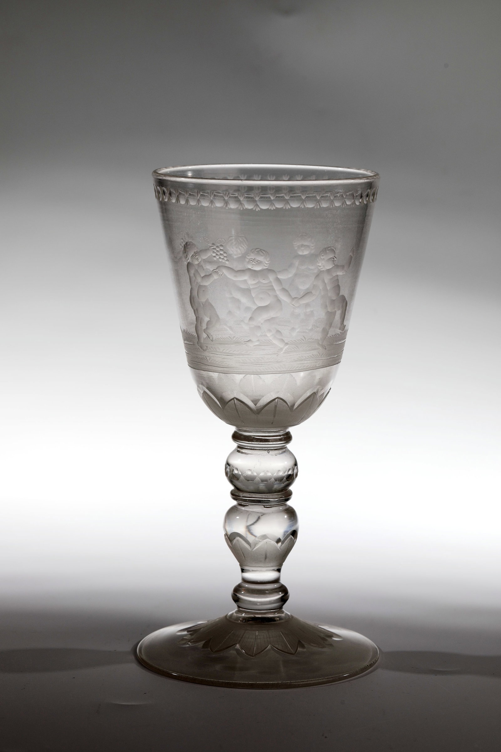 Cup with Bacchic putti in the round dance: Goblet with Bacchic putti in the Reigen Potsdam, around 1720 in the manner of Gottfried Spiller Colourless, slightly glass-diseased glass. Slightly rising disc base with ground tear-off. Baluster shaf