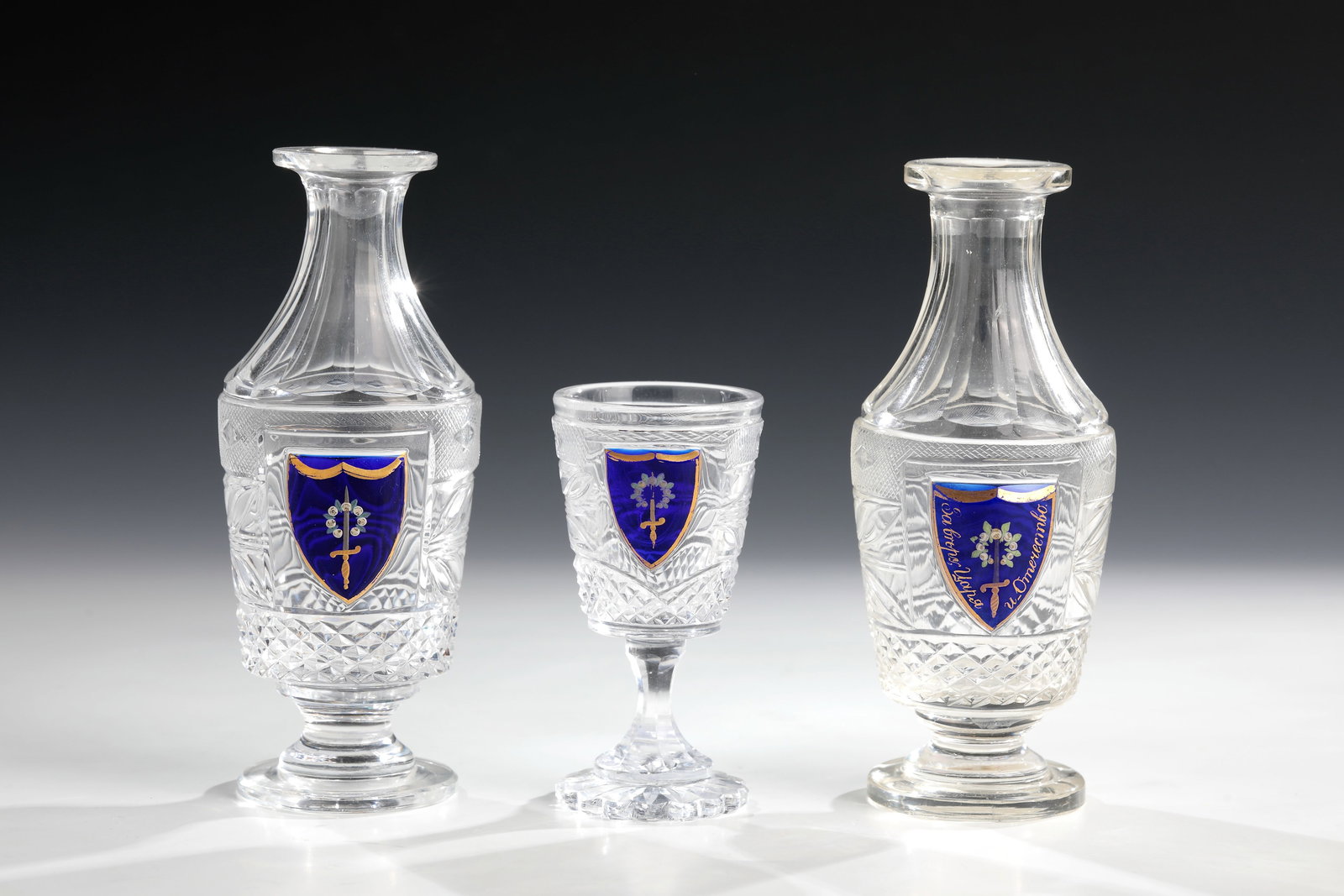 Pair of bottles and small foot cup from the service of Tsar Nicholas I from the Peterhof Palace: A pair of flacons and a small foot cup from the service of Tsar Nicholas I from the Peterhof Palace Imperial Glass Manufactory, designed by I. Ivanov, c. 1827-28 Colourless glass with rich cut