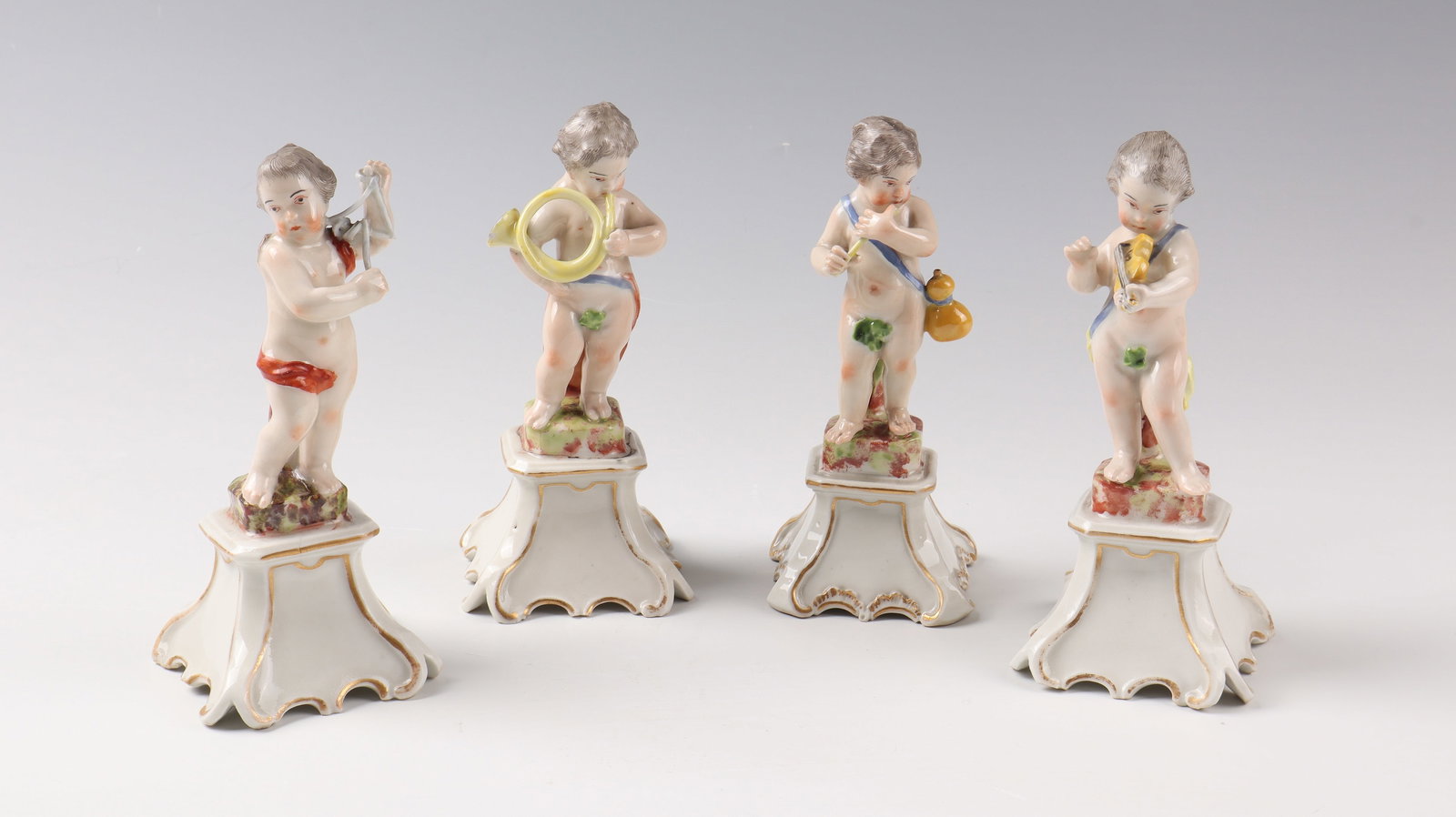 Four music-making putti: Four music-making putti Ludwigsburg around 1768-70, after a model by Johann Heinrich Schmidt porcelain, polychrome painted. On curved, gold-contoured pedestals, putti with triangle, French horn,