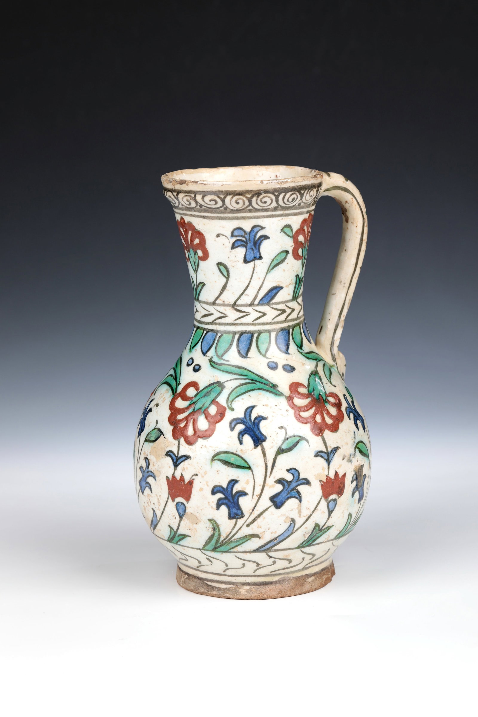 Mug with carnation and hyacinth decoration: Jug with carnation and hyacinth decoration Turkey, Iznik, 17th century Pear-shaped, white engobed wall with painting in blue, green and iron red, partly contoured in black, glazed. At the neck two orn