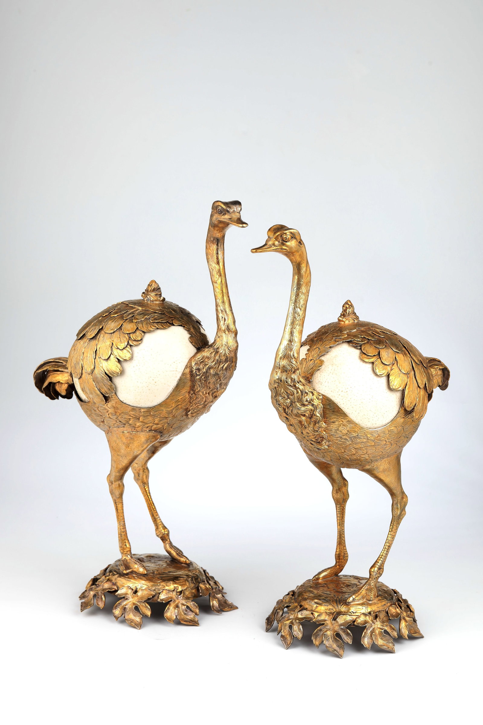 Important ostrich couple: Important ostrich pair Germany, probably Hanau, E. 19th century. Ostrich eggs and gilded, finely executed silverwork. Arched pedestals with embossed and engraved floral ornaments resting on eight or n