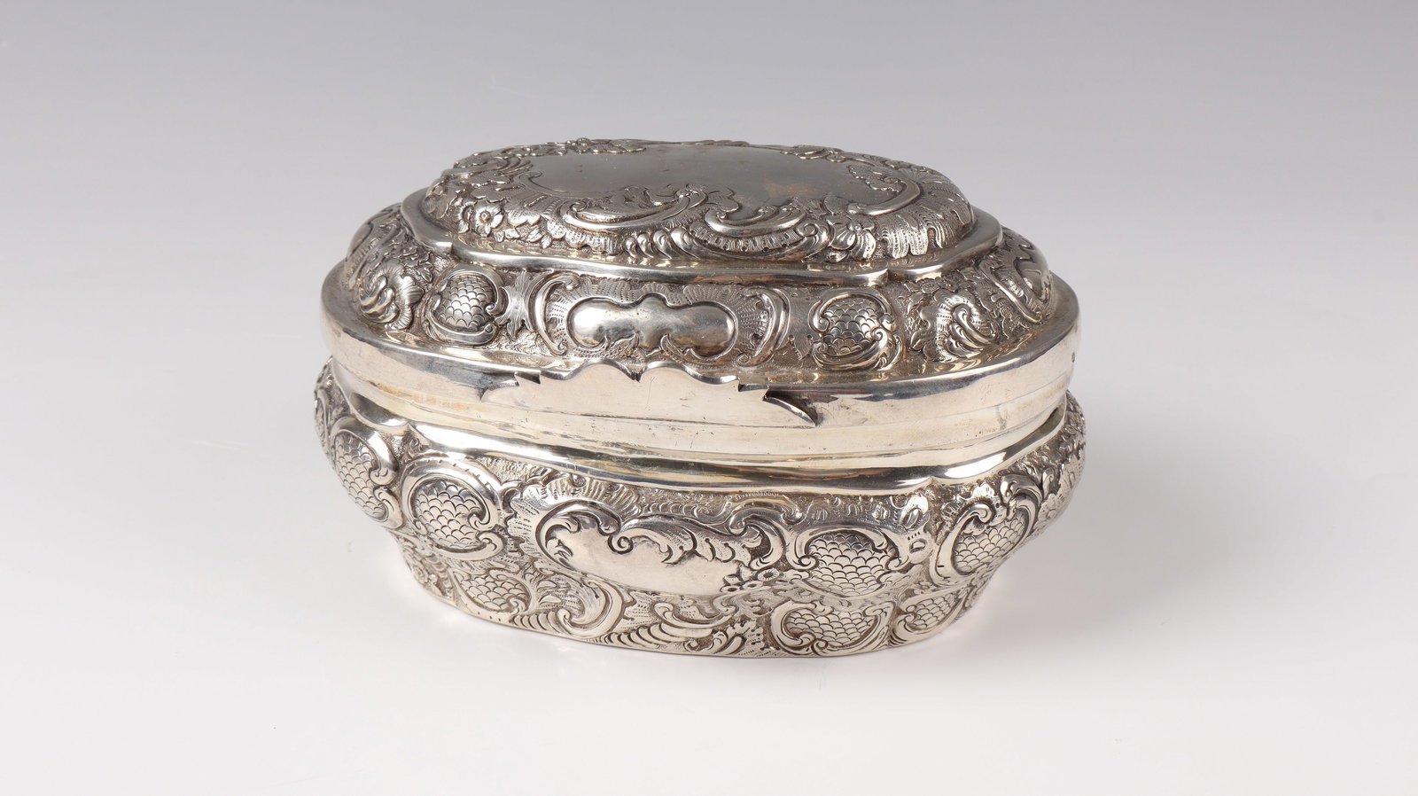 Large silver tin: Large silver box Austria, 1753 In cross-section, oval box with hinged lid and finely embossed and re-engraved ornaments from the period of transition from Baroque to Rococo: cartouches with scale patt