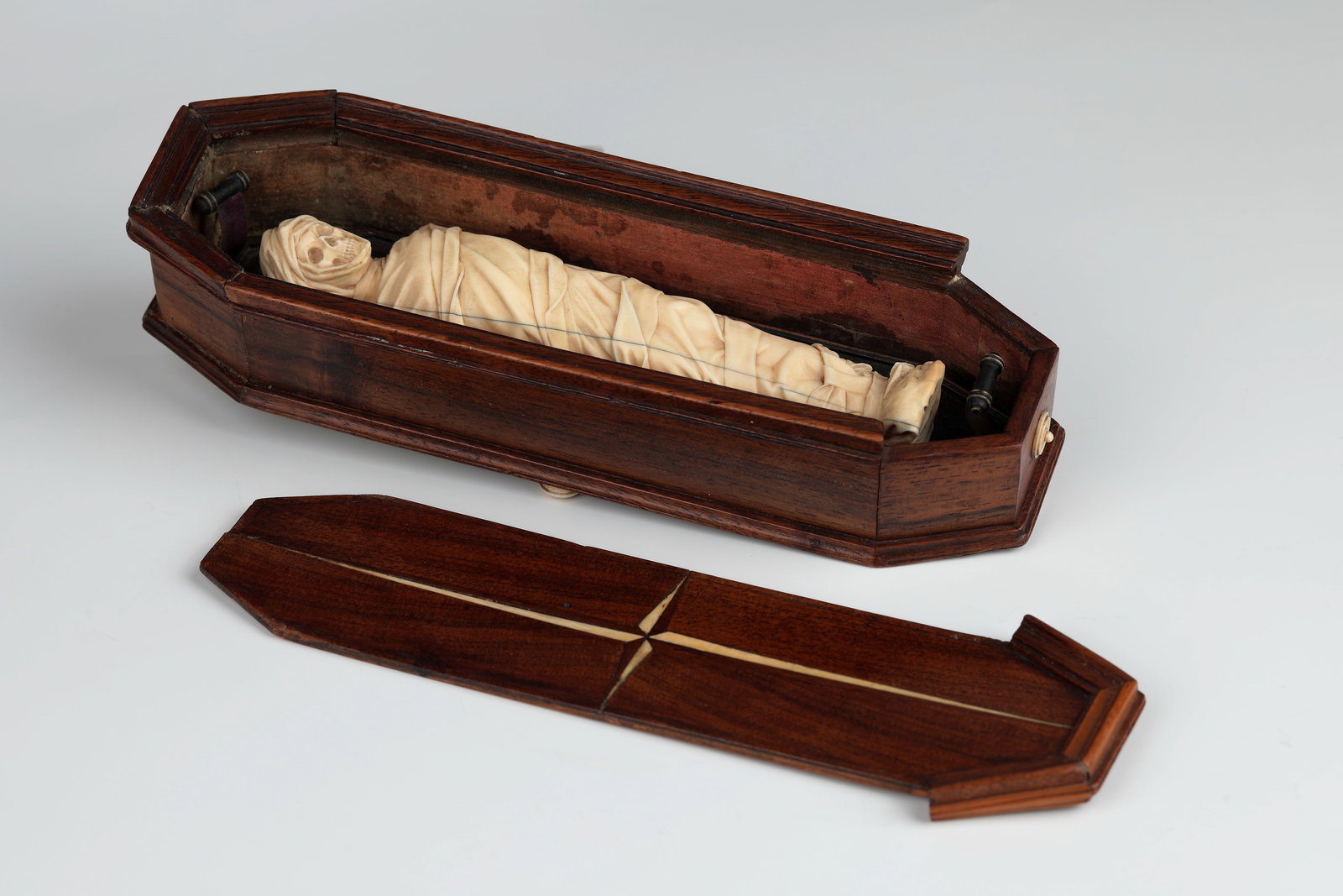 Memento mori: Tödlein in Coffin: Memento mori: Tödlein in Coffin Alpine, 18th/19th century Eight-sided coffin resting on four feet, the inner walls lined with patterned paper, partly profiled, the sliding lid decorated with inlays. 