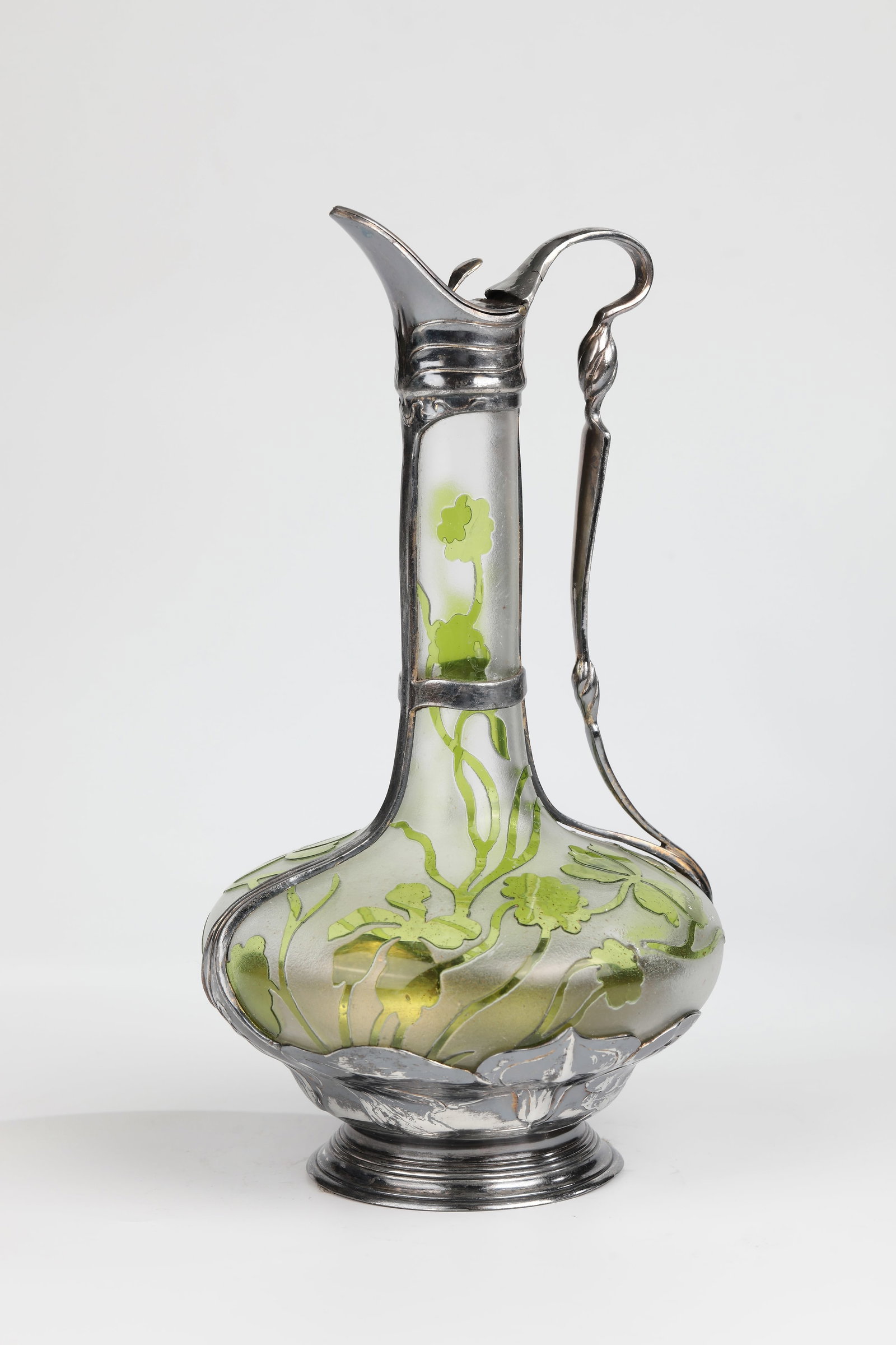 Carafe with 'ORIVIT' mount: Carafe with 'ORIVIT' mount Orivit AG, Cologne-Braunsfeld, c. 1903 Colourless, matt etched glass, light green overlay. Etched floral decoration in relief all around. Mount made of 'Orivite' metal.