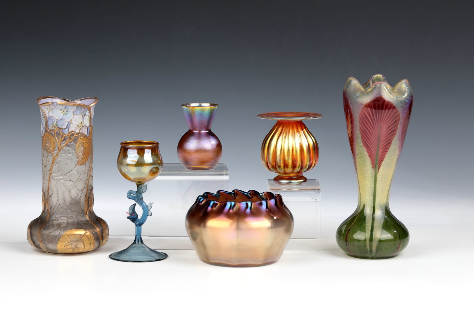 Six vases: Six vases including Loetz Wwe., Klostermühle, WMF, Geislingen, from 1892 Various designs and shapes. H. 6.3 - 17 cm. Condition: A vase with a chip below the edge of the mouth.