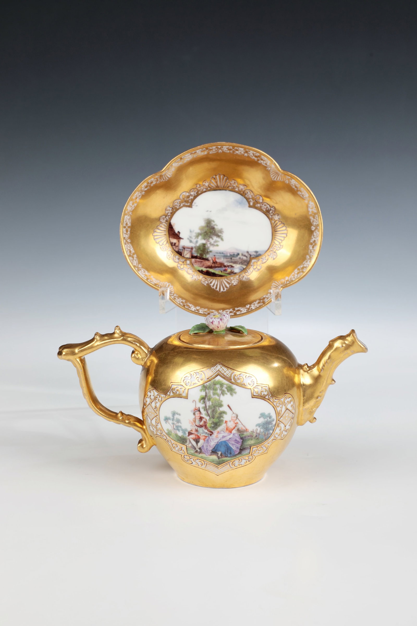 Teapot and saucer with cotton wool scenes: Teapot and saucer with cotton wool scenes Meissen, c. 1745-50 Surface-filling gold background, gallant scenes in park landscape or landscape depiction with architecture and staffage in recessed
