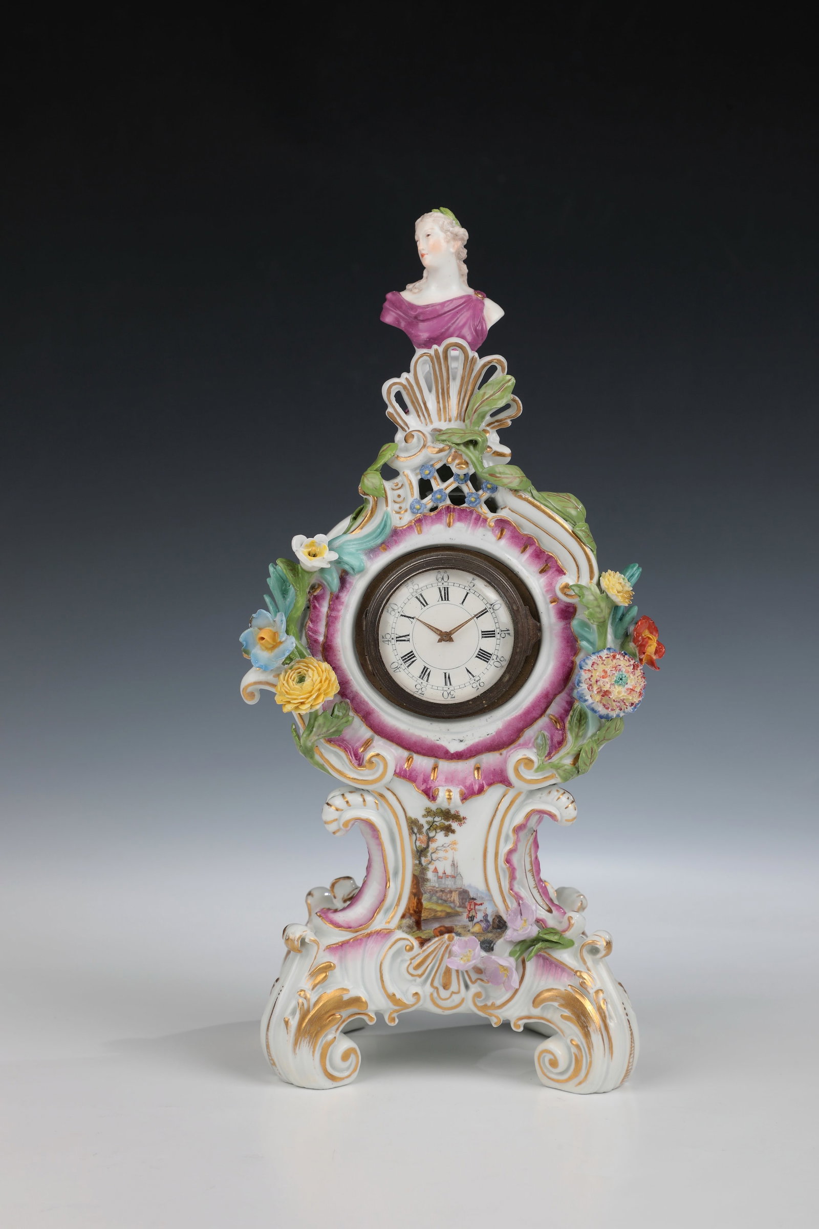 Small Table Clock: Small table clock Meissen around 1760 Round clock case framed by sculpturally applied, finely modelled flower tendrils. Shell-shaped crowning with a small bust of Apollo. On the front side, a
