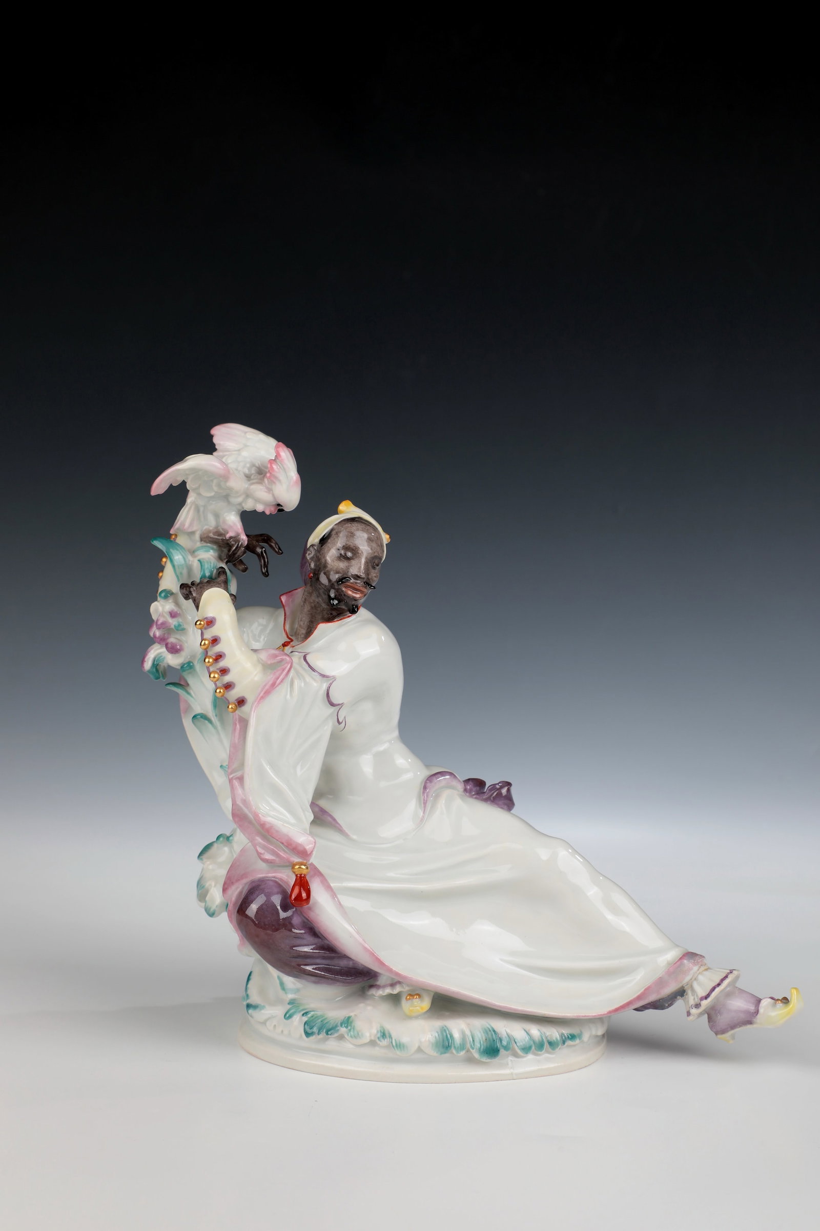 Figurine with cockatoo: Figure with cockatoo Meissen, 1934 - 1945, Paul Scheurich (design) A man in a rich robe leaning against a palm tree above an oval, overgrown pedestal, a cockatoo crouching on his right hand with his