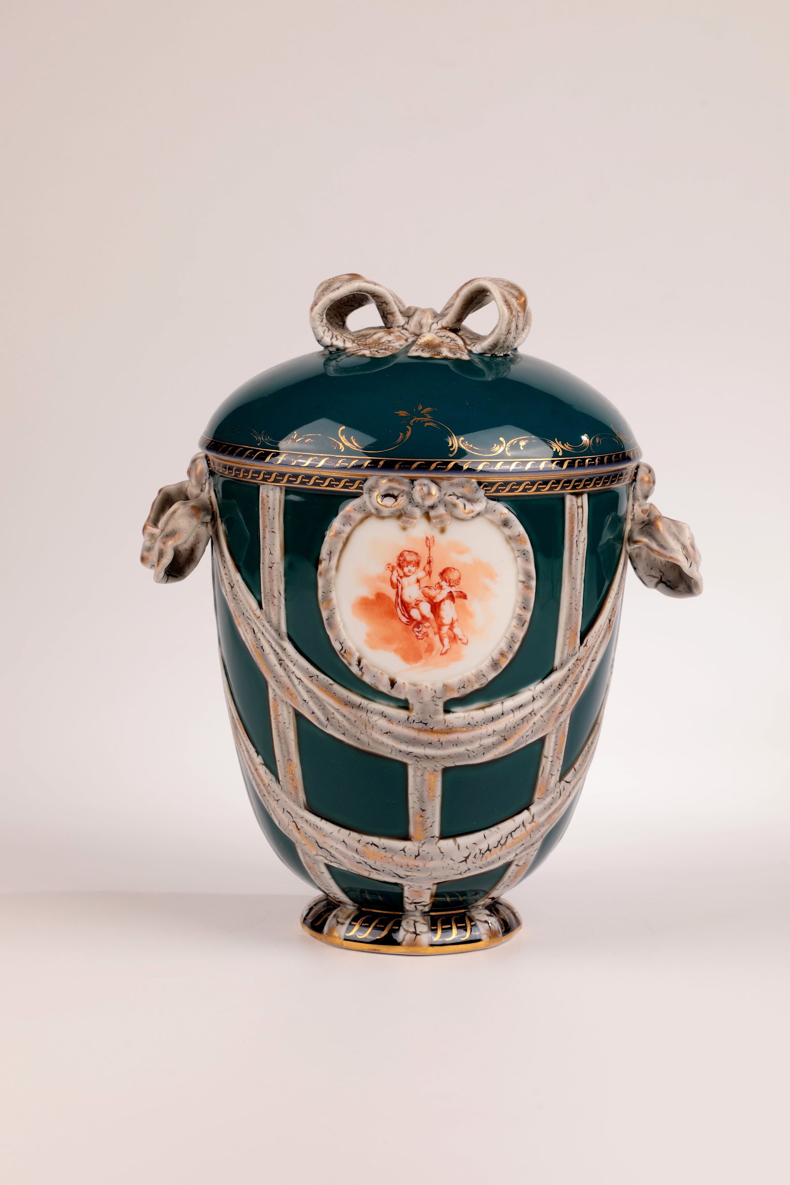 Lidded vase: Lidded vase KPM Berlin c. 1910 Iron red camaieu painting of a pair of cherubs in clouds or flowers in two cartouches, petrol-coloured background. Gold-heightened ribbon decoration, gold staffage
