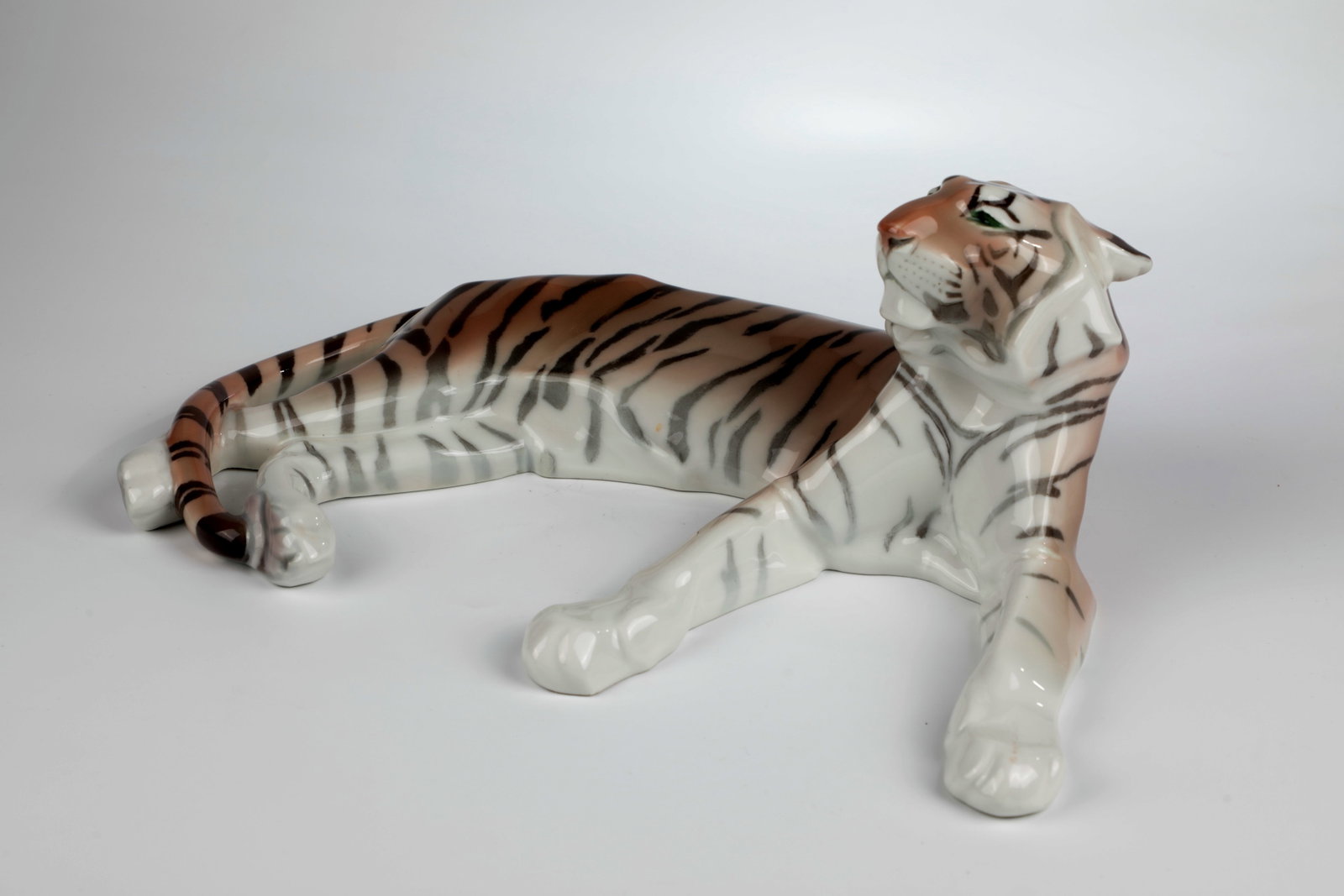 King Tiger: King Tiger designed by Anton Puchegger 1911, executed by KPM Berlin 1925 Lying on the ground with outstretched paws. Colorful, naturalistic underglaze painting. Signature on the reverse: A.Puchegger
