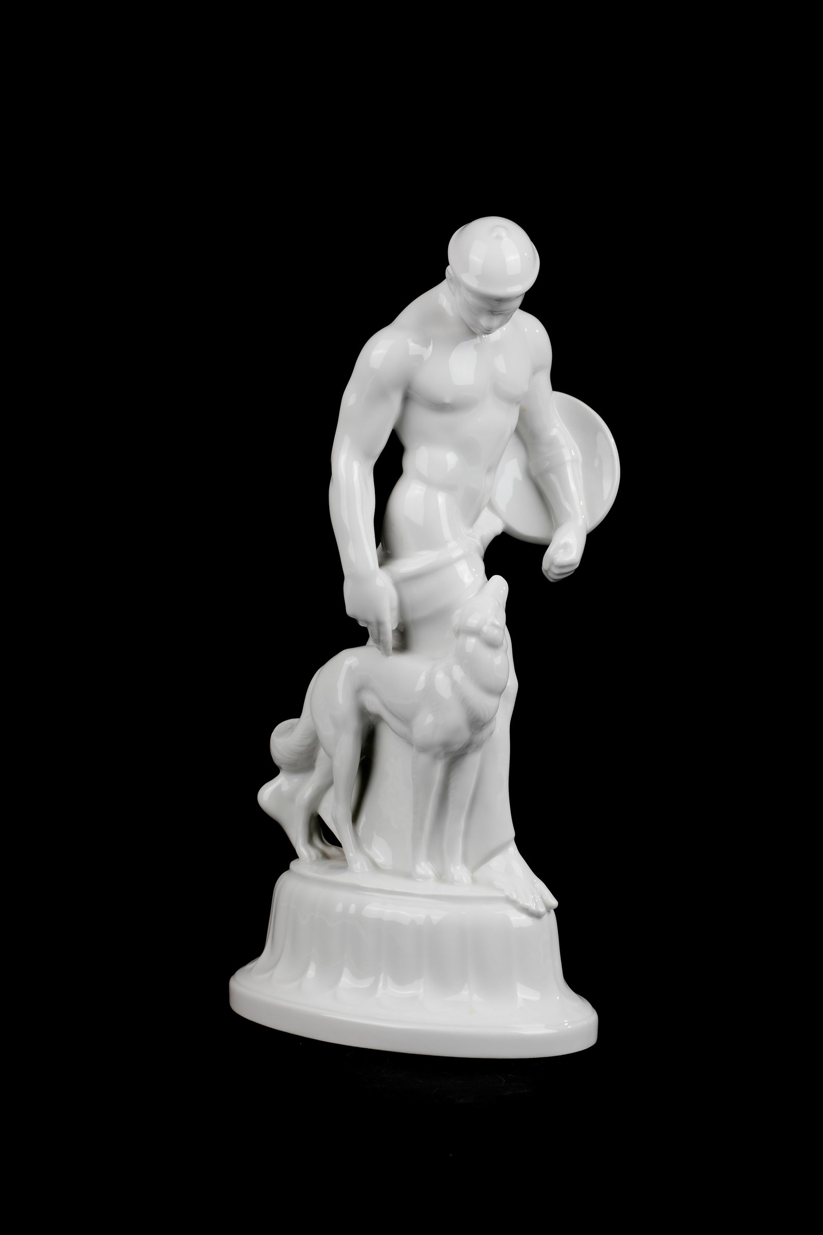 Gote with dog: Gothic with Dog designed by Adolf Amberg 1910, manufactured by KPM Berlin 1919 porcelain, white, glazed. Helmeted male figure with shield and long loincloth, at his side faithfully looking up dog.