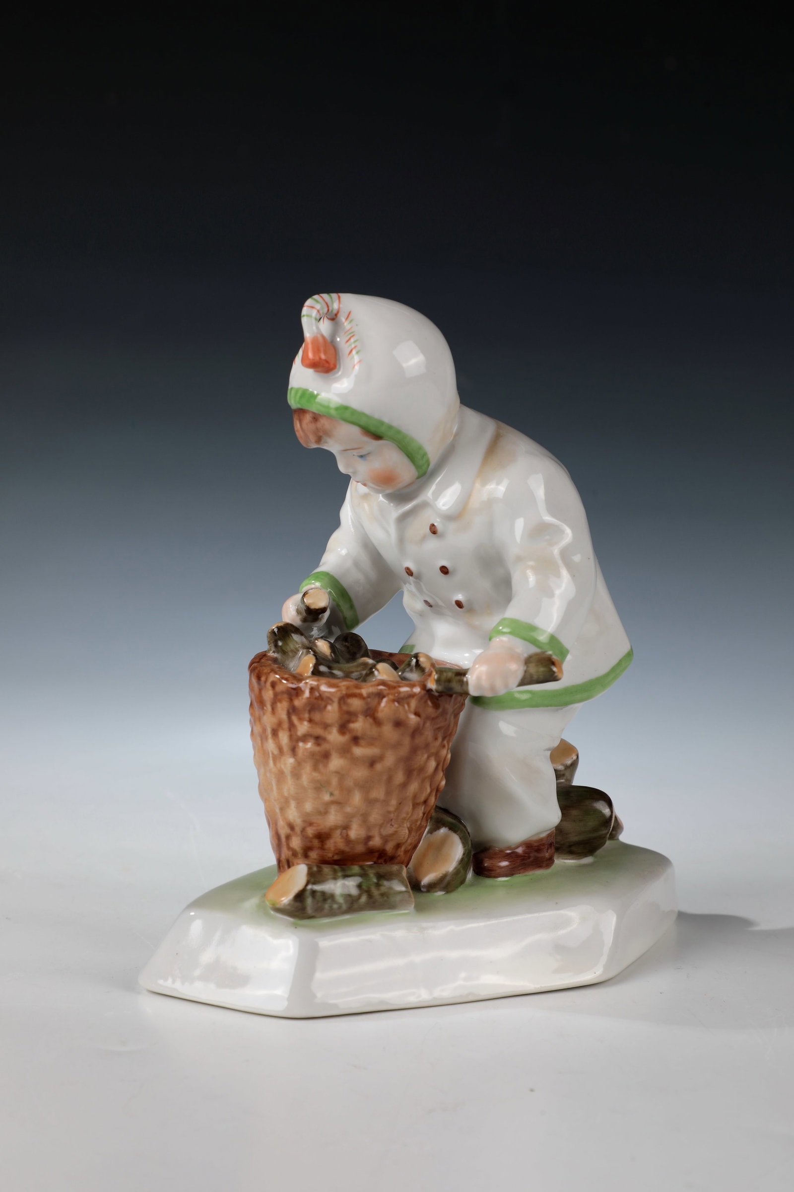 Firewood collector: Firewood collector Zsolnay, Pécs, design probably András Sinkó, 1st half of the 20th century Fully sculpted, naturalistically painted figure of a boy putting firewood in a basket. In