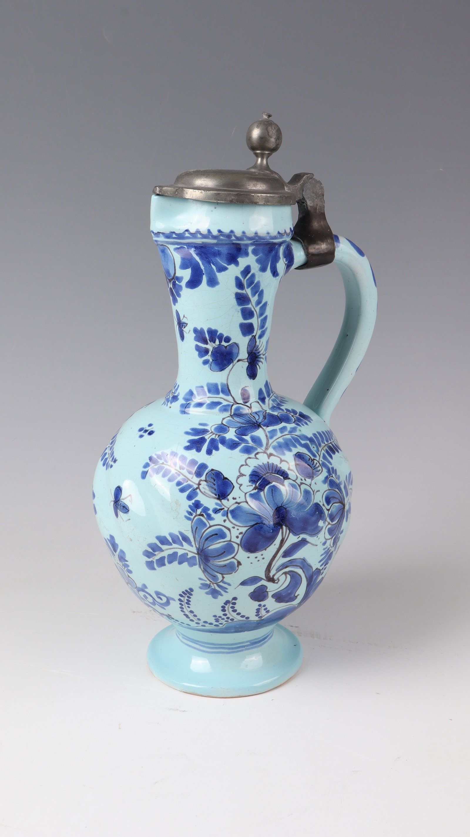 Narrow-neck jug: Narrow-necked jug Hanau around 1700 The spherical wall ribbed diagonally. Decor in blue painting on a light blue background: flowers, leaves and insects. Strap handle with tin lid. In the floor