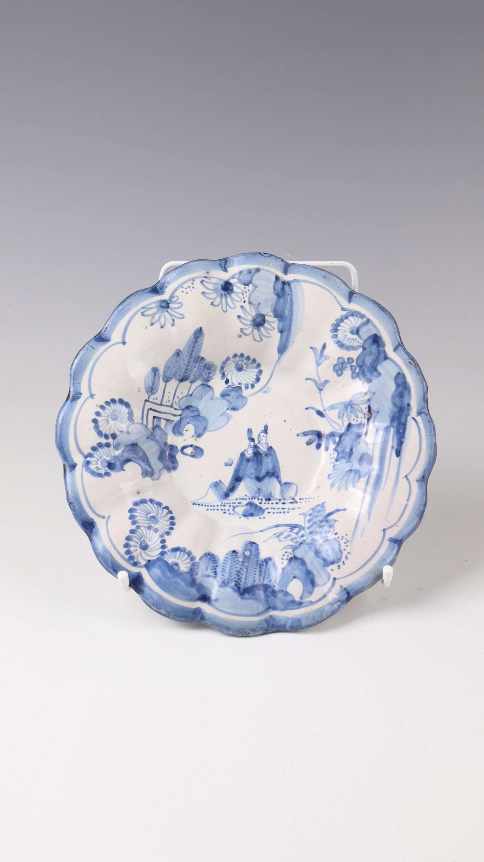 Small hump plate with chinoiserie: Small humpback plate with chinoiserie, Frankfurt around 1700 In the mirror and on a domed flag, two Chinese figurines in stylized landscapes with exotic vegetation. Execution in blue painting. lip
