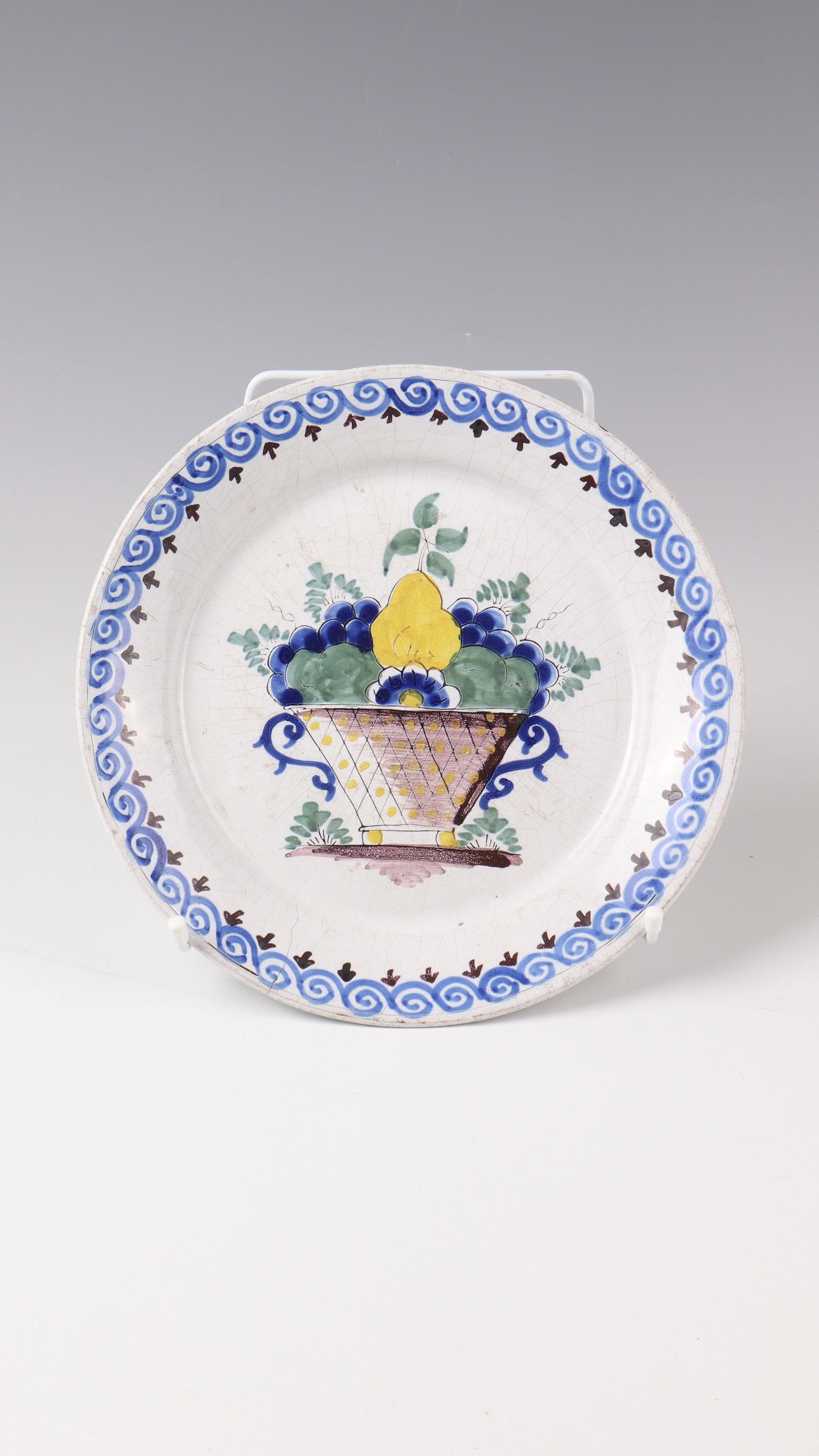 Plate: Plate Bayreuth around 1750 White glazed with fine painting in bright sharp-fire colours: fruit basket and feathery leaf branches in the mirror. On the trail wave pattern. Maler Johann Clarner. Hair