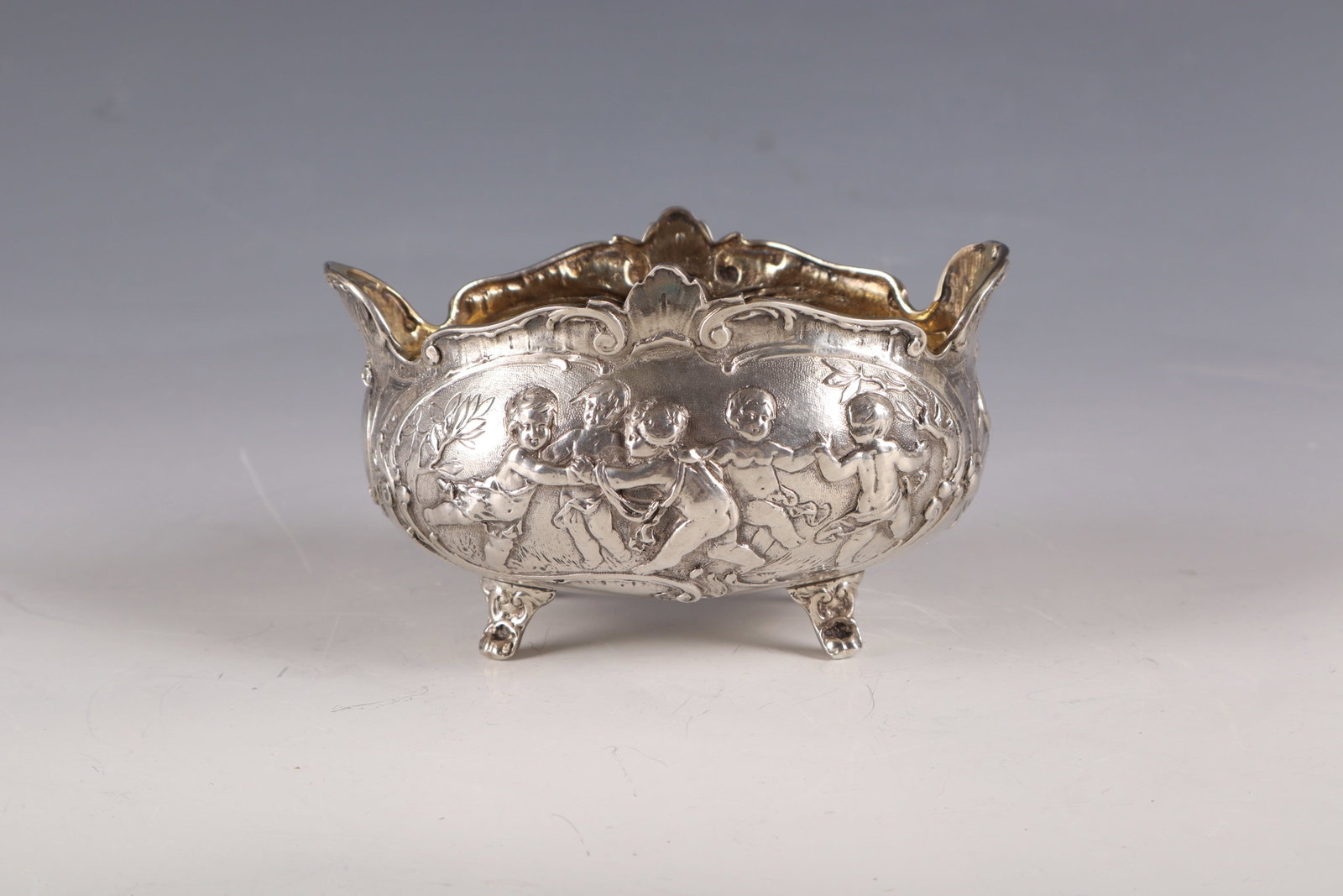 Shell: Bowl German, c. 1890 silver, gilded inside. On four paw feet bulbous body with relifed putti decoration on a punched background and between tendrils. The edge of the muzzle passable. Hallmarked on