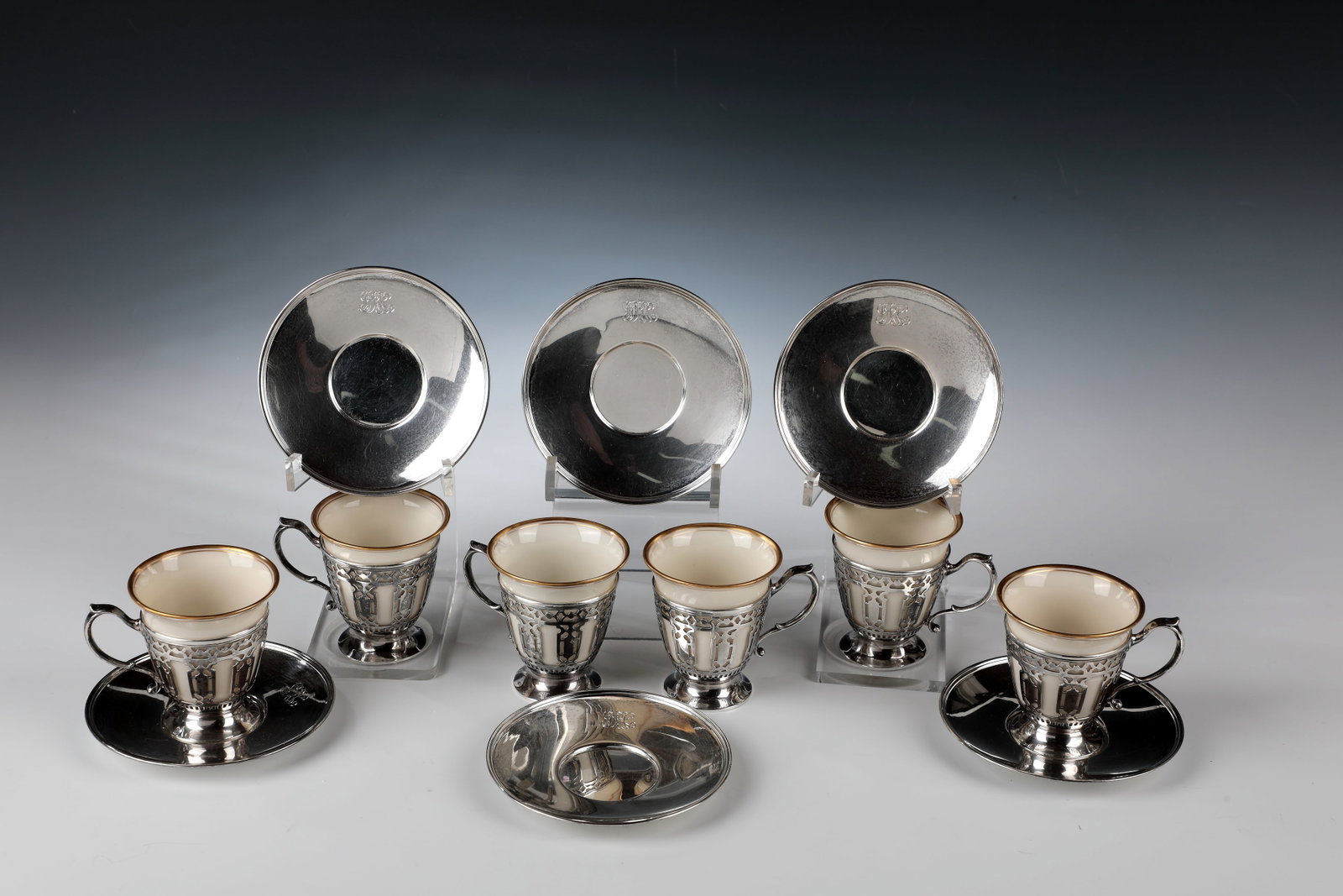 Six mocha cups with saucers: Six mocha cups with saucers Tiffany & Co., New York, 1910-1930 Sterling silver mounts by Tiffany & Co., openwork and with curved handles. Saucer with engraved owner's monogram. Removable porcelain