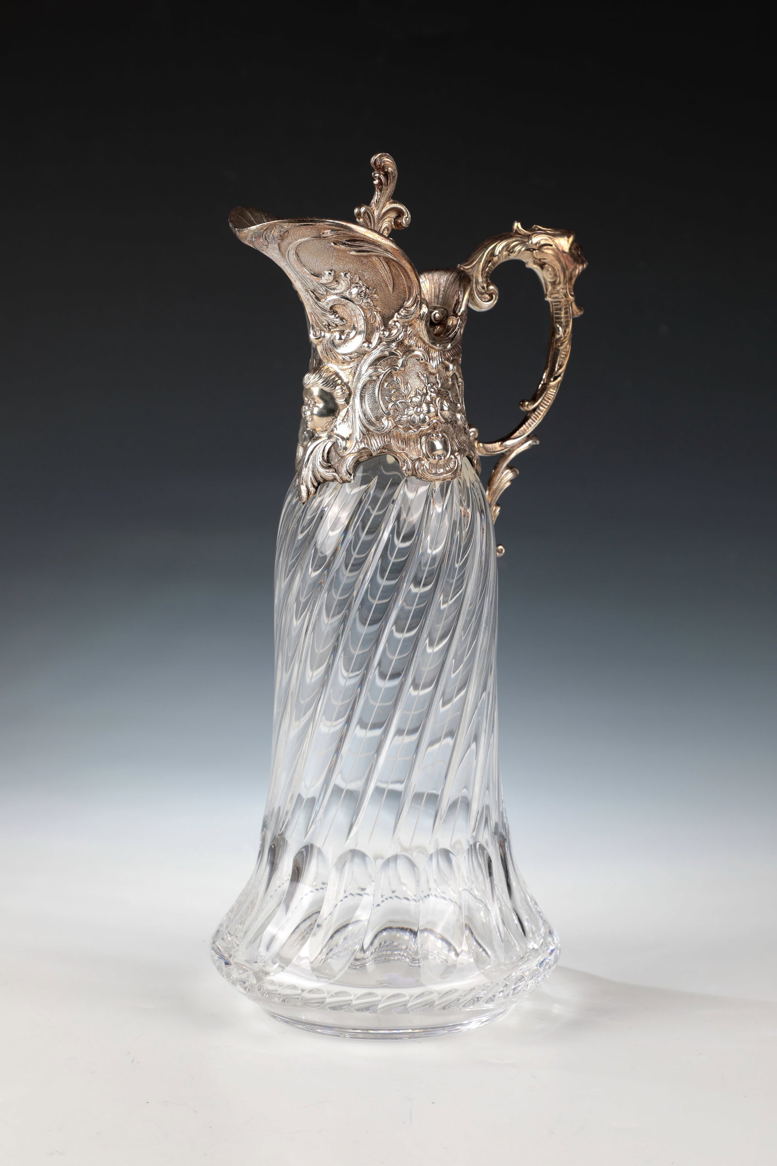 Carafe with silver mount: Decanter with silver mount Portugal, 20th century Colourless glass with spirally twisted wall. Silver mount in rococo forms with flower and rocaille decoration, curved spout and elaborately designed