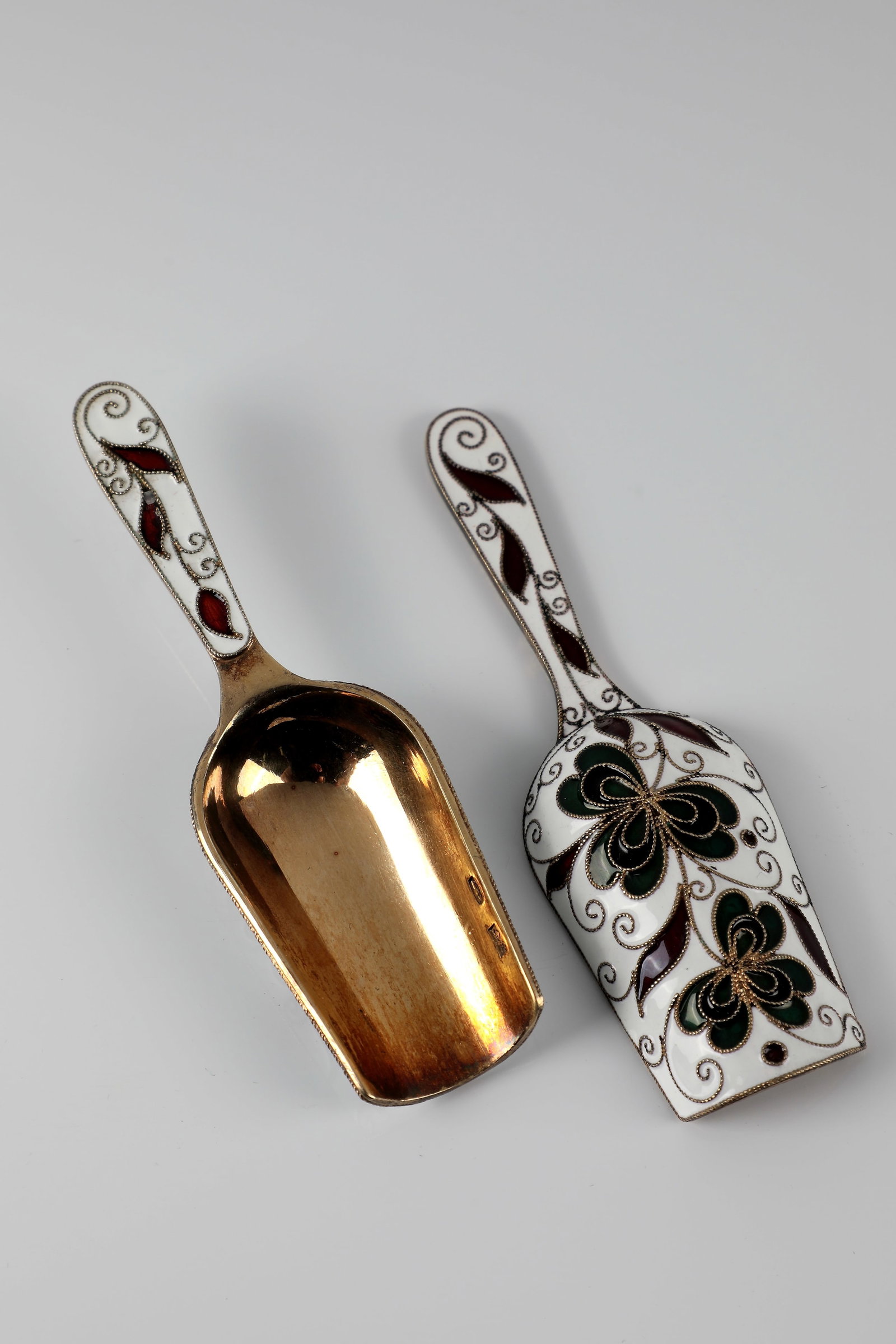 A few sugar spoons: Pair of sugar spoons Probably Soviet Union, 2nd half of the 20th century, silver, gilt. Shovel worked in filigree and cloisonné technique on a white enamel background. Decoration of stylized flow
