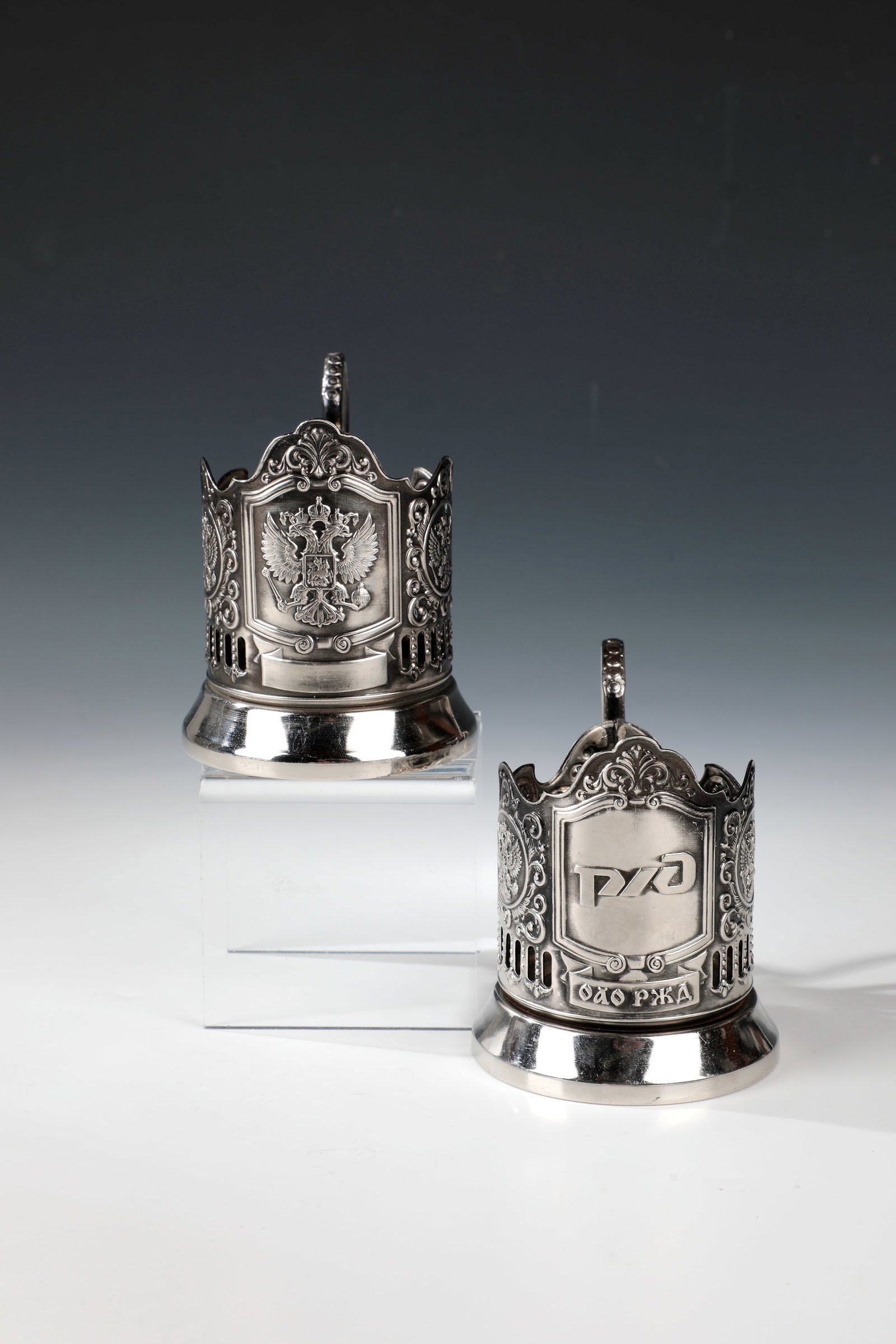 Pair of Tea Glass Holders: Pair of Tea Glass Holders Russia, 20th Century Embossed. partly joked precious metal with double-headed eagle and tendril decoration. H. 10 cm