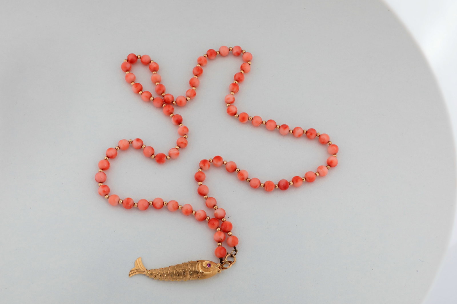 Coral necklace with fish pendant: Coral necklace with fish pendant Fish pendant made of 18 kt/ 750 GG (hallmarked), with eye made of faceted mane spinel, on individually knotted coral necklace. L. Chain without pendant approx. 28 cm;