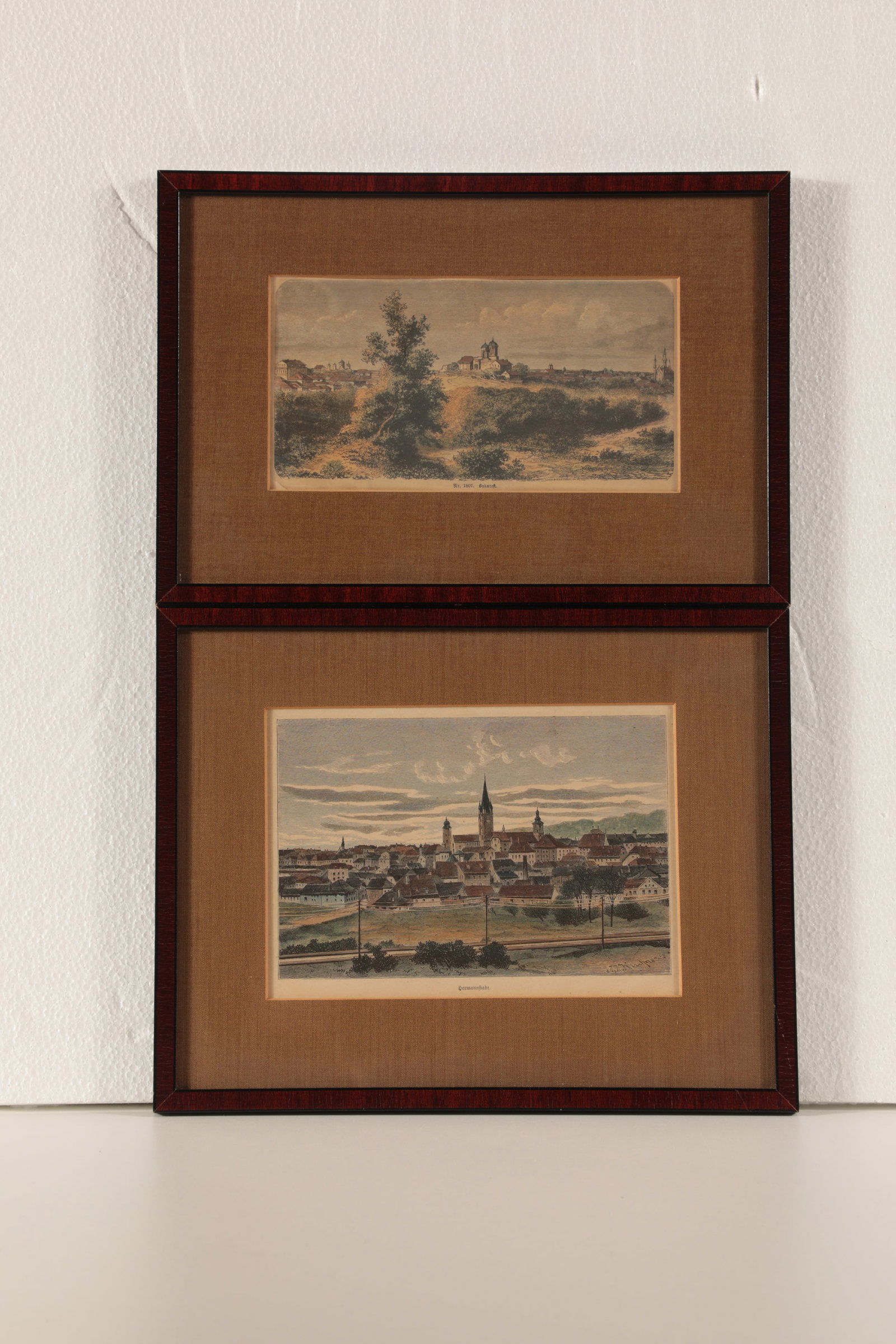 Sibiu and Bucharest: Sibiu and Bucharest 19th century Two small wood engravings with city views of Sibiu and Bucharest, inscribed and coloured by hand. One signed in the printing plate: J. J. Kindinger (?). Each framed