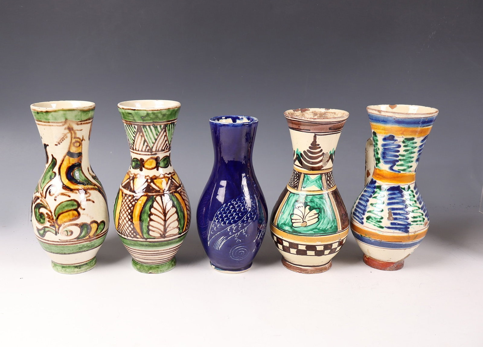 Mixed Lot of 5 Pear Jugs: Five pear jugs of various pear jugs. Manufactories, 19th and 20th centuries Polychrome floral ornaments on ivory or cobalt blue ground, partly decorated with geometric borders, partly with traces of u