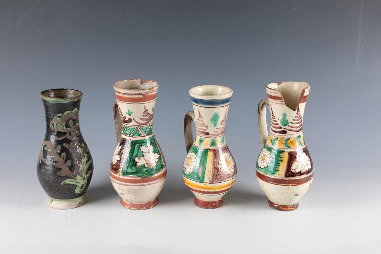 Four pear jugs: Four pear jugs Transylvania, Thorenburg and Nimesch, 19th century Stylised floral decoration in ochre, brown, green and blue on a butter-coloured background or in green on a dark background. Partly
