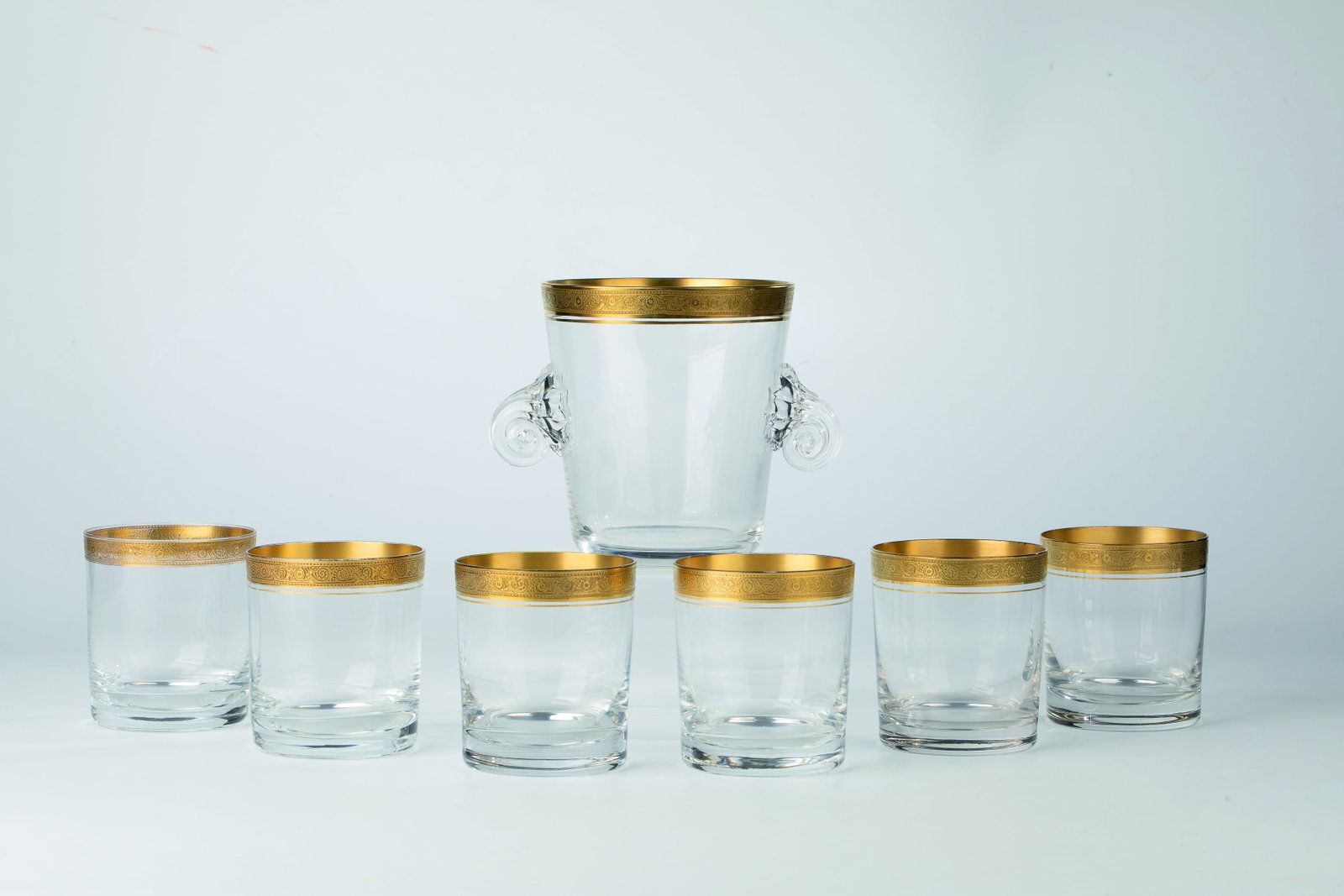 Six cups and ice buckets: Six Beakers and Ice Buckets France, 20th Century Colorless glass with gilt lip rim, on top of which is a circumferential relief frieze. The ice bucket with two fluted decorative handles applied to
