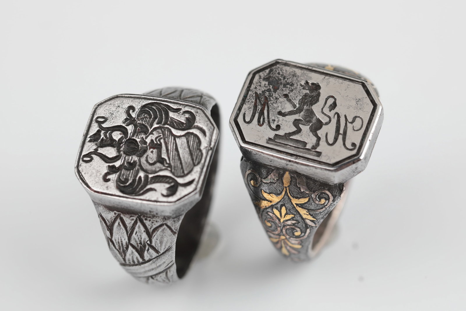 Two signet rings: Two signet rings 19th century One ring worked on the outside as a laurel wreath, the second decorated with floral, partly gilded ornaments. Sealing surface with recessed coat of arms or rising lion