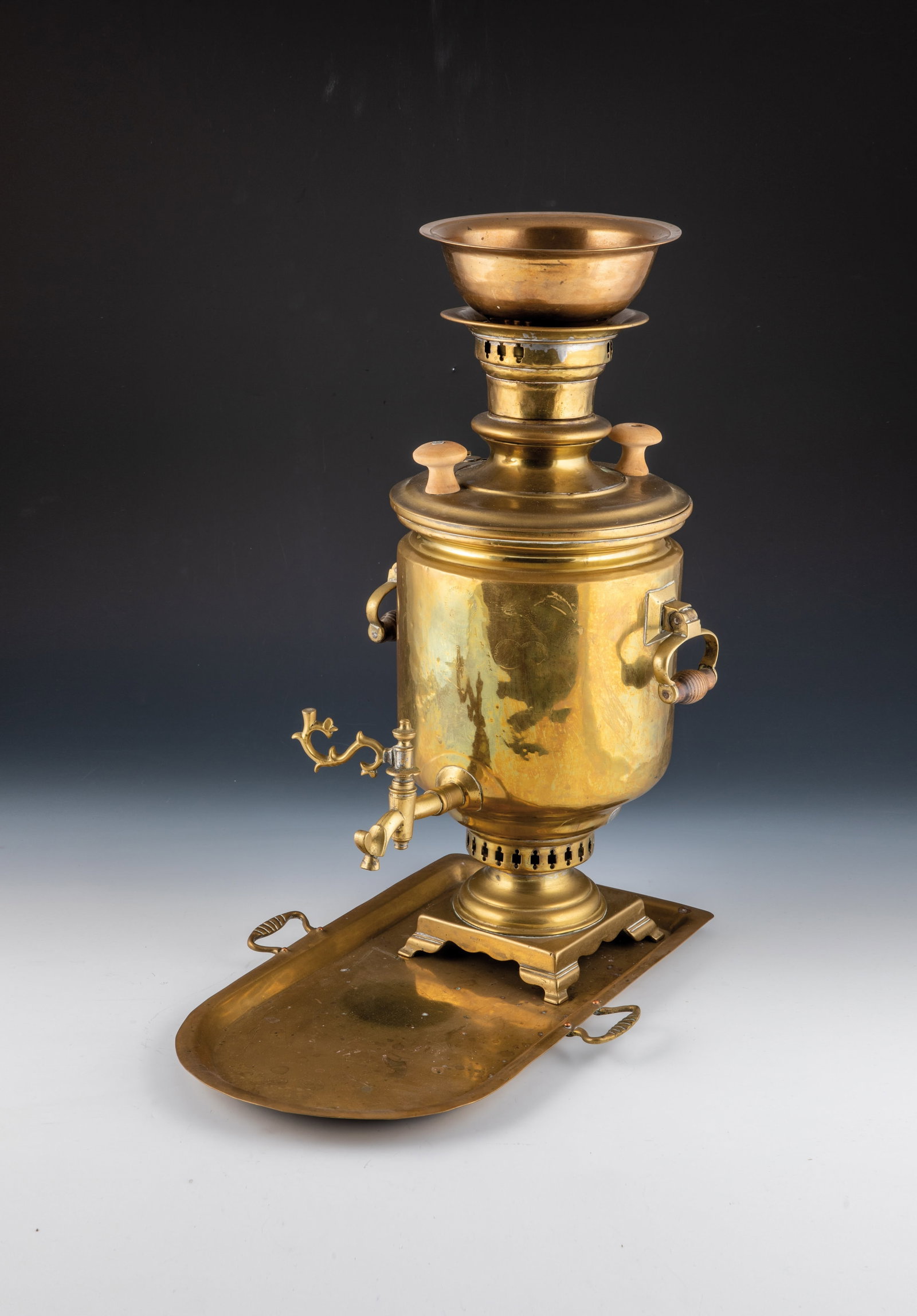 Samovar with coaster: Samovar with coaster Russia, Tula, E. 19th century, brass. On four feet and square plinth. Wooden handles, partly new. Frontal company stamp with four medals. H. 51.5 cm