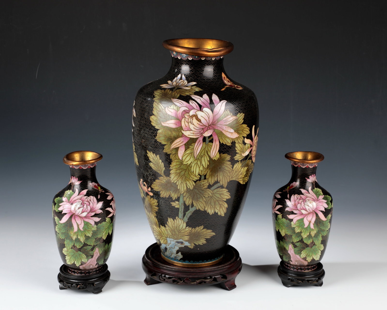 Cloisonné vases, 3 pieces: Cloisonné vases, 3-part China, c. 1900 All around with chrysanthemum and cherry blossom decoration on a black background. Mouth partially dented. Surface in places age-related deposits, minor