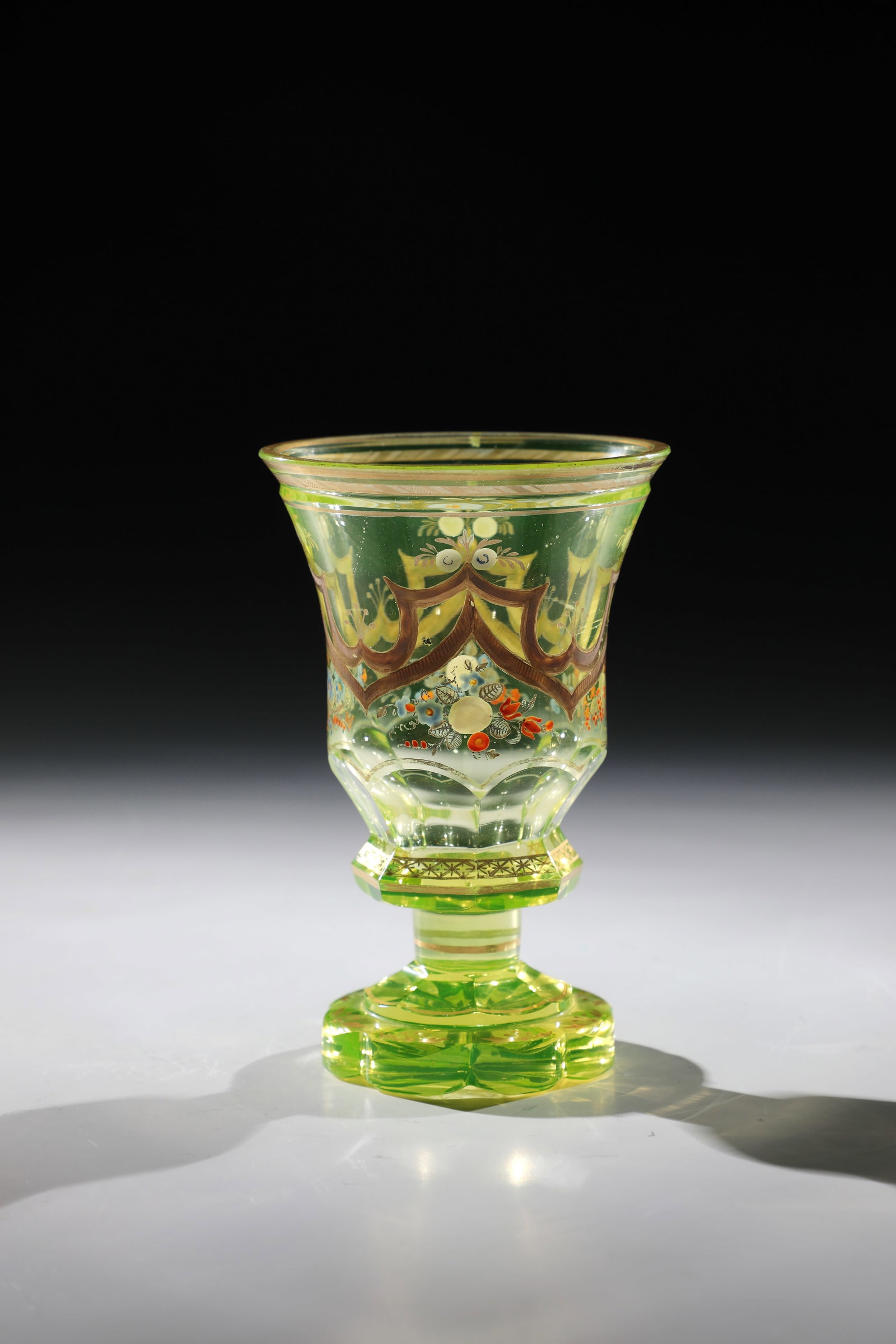 Uranium Glass Foot Cup: Uranium glass base cup Bohemia, mid-19th century. Eight-pass foot, lower wall area peeled. Decor of colourful enamel, silver and polished gold painting: flower arrangements and hanging ornaments. lip