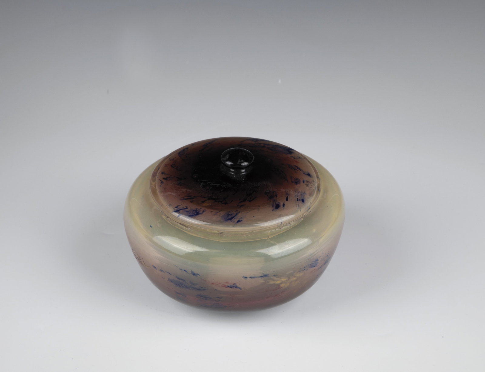 Lidded jar: Lidded box Emile Gallé, Nancy, c. 1896/97 Colourless glass, with multi-coloured flat and fluffy powder inclusions. On the wall in engraving inscription: ''Gallé''. Bumped. H. 10 cm; D. 14
