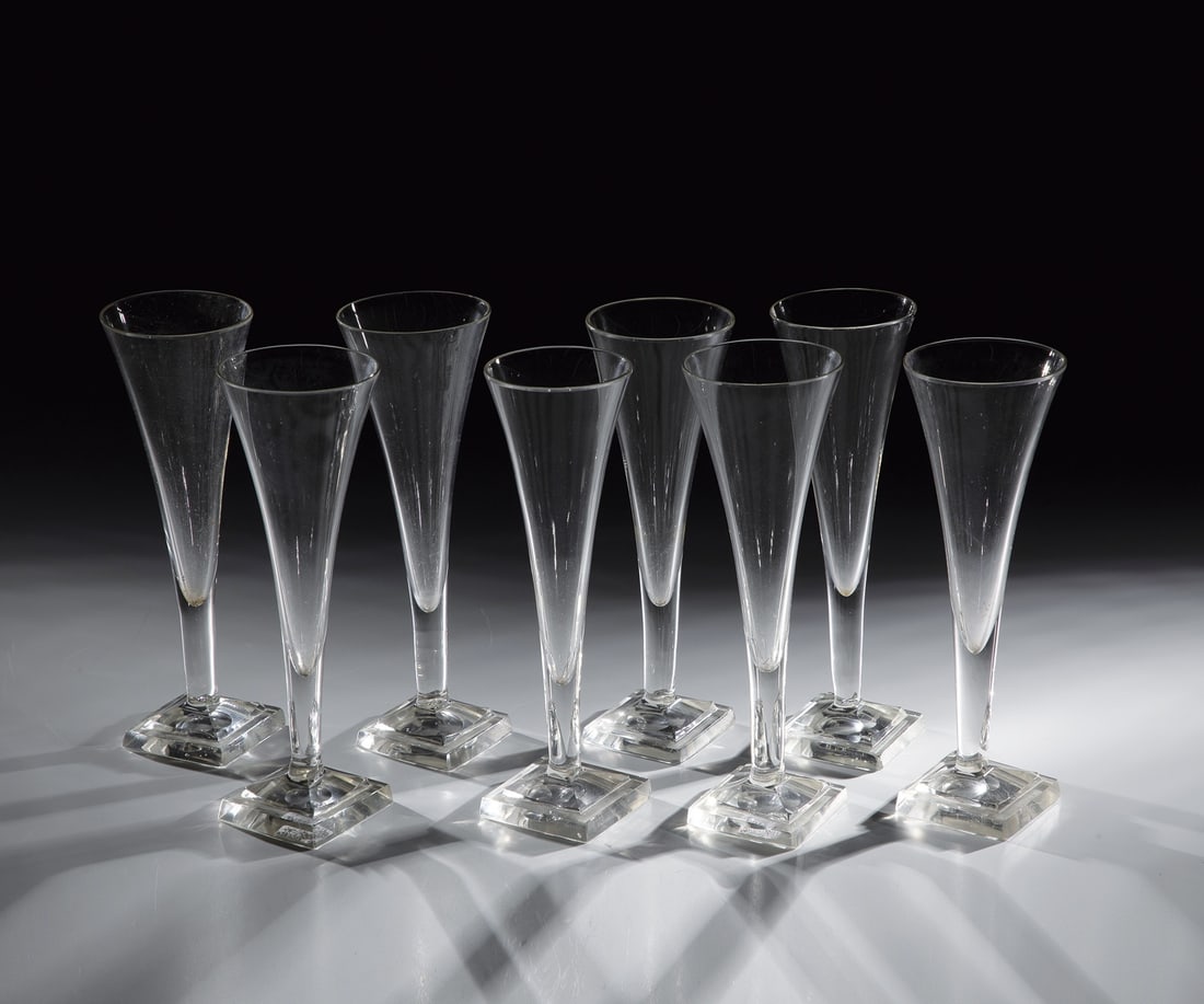 Set of eight champagne flutes: Set of eight champagne flutes, France, 18th / 19th century, colourless glass with ground tear-off. Square plinth, partly chipped. Trumpet-shaped cuppa. H. 20 cm Satz acht Sektflöten Frankreich